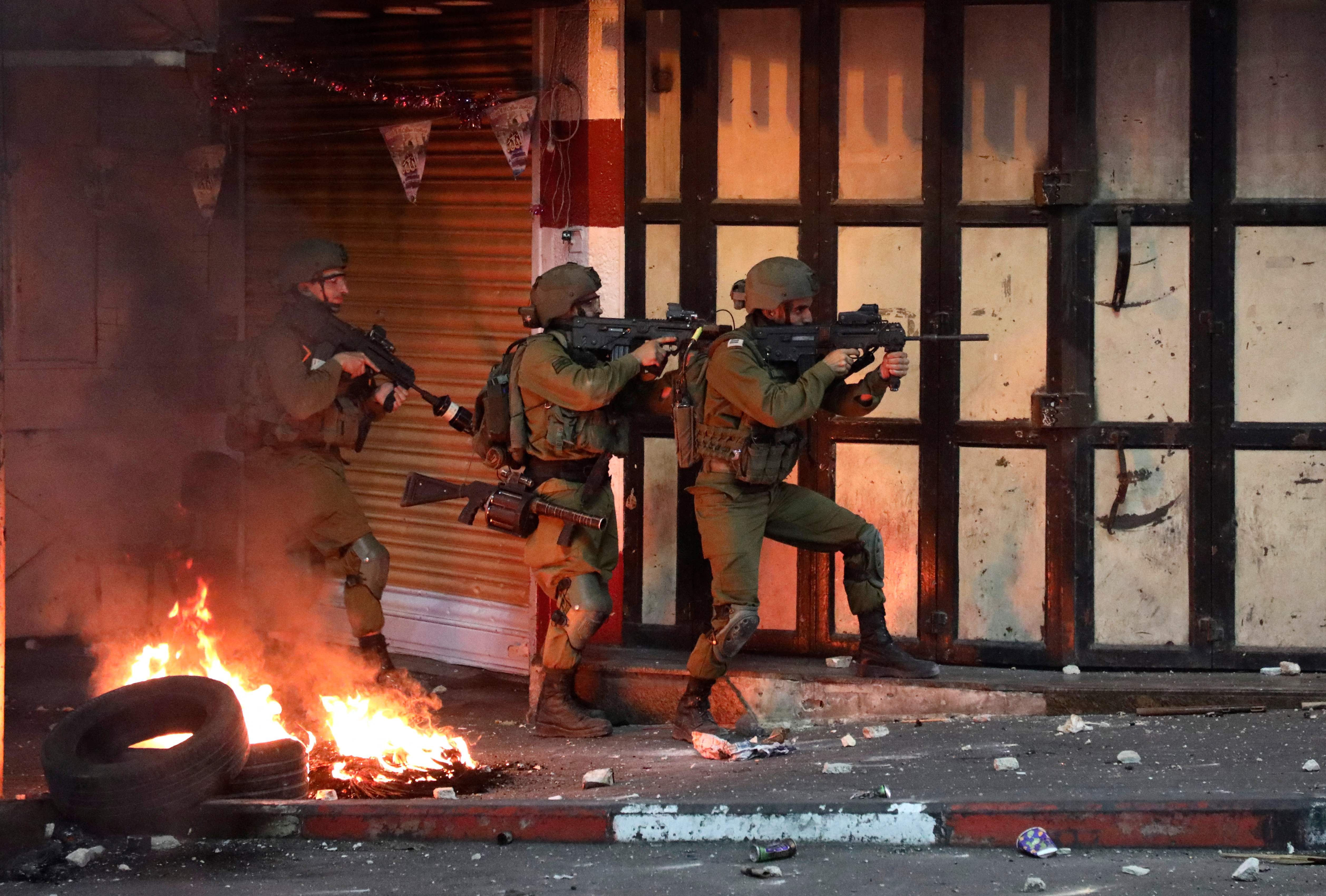 Israeli soldiers take aim during clashes with Palestinian protesters in Hebron