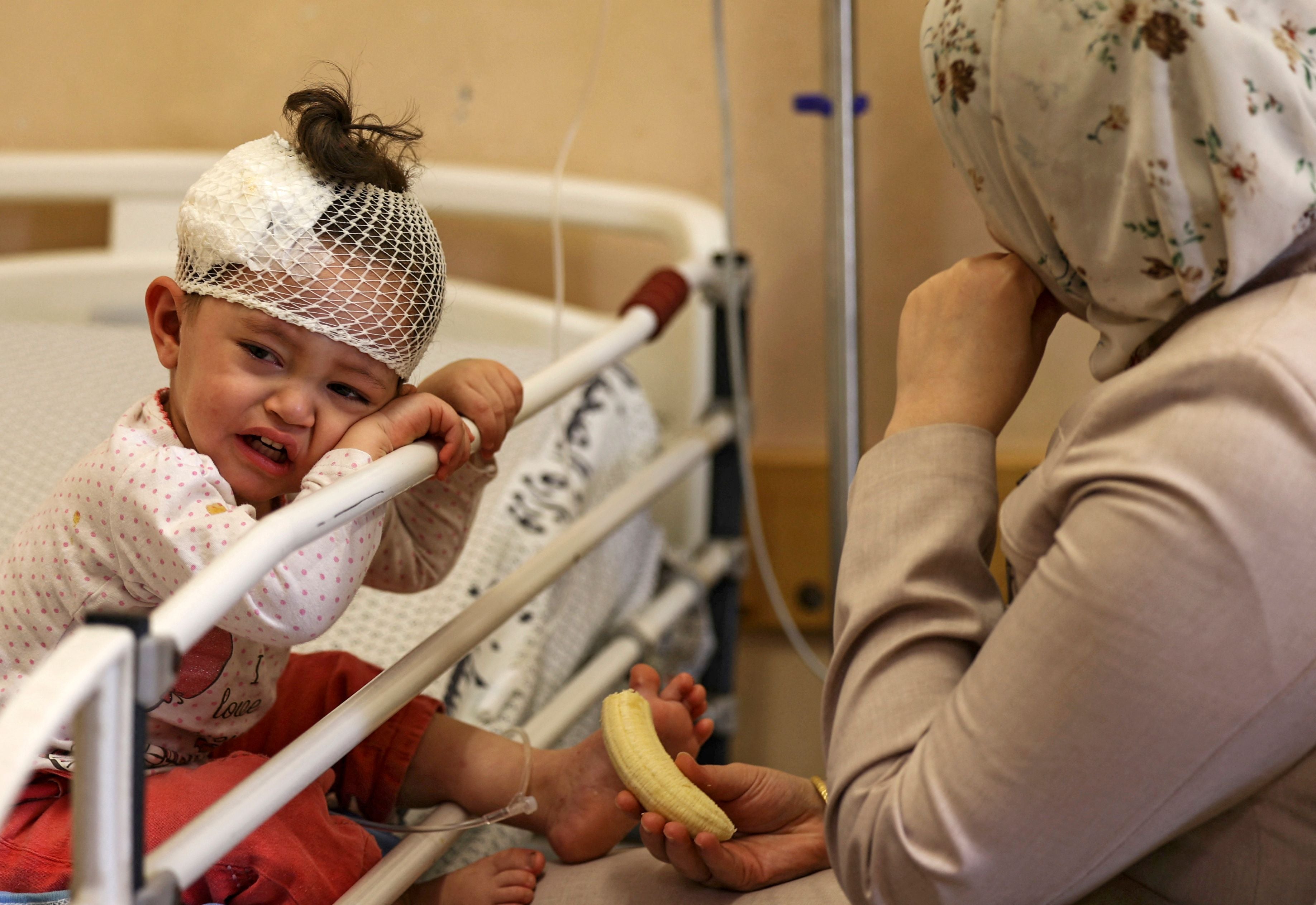 A Palestinian mother sits with her daughter, who was wounded in overnight Israeli air strikes on the Gaza Strip