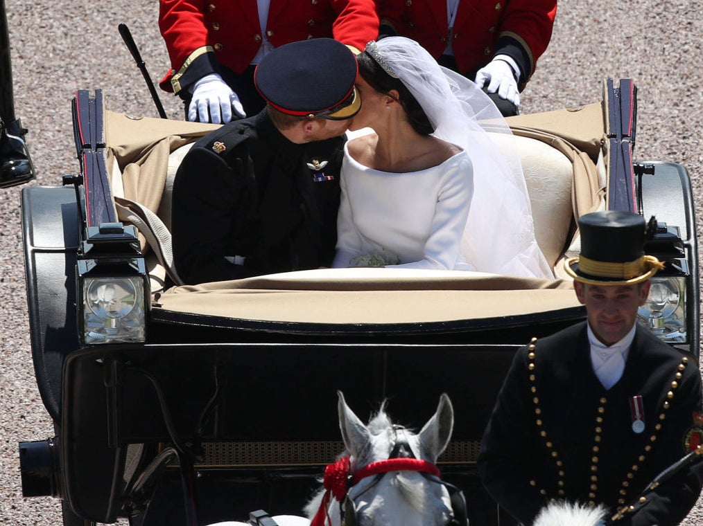 Prince Harry, Duke of Sussex kisses his wife Meghan, Duchess of Sussex, as they pass through the Cambridge Gate into the grounds of Windsor Castle at the end of their carriage procession in Windsor, on 19 May 2018