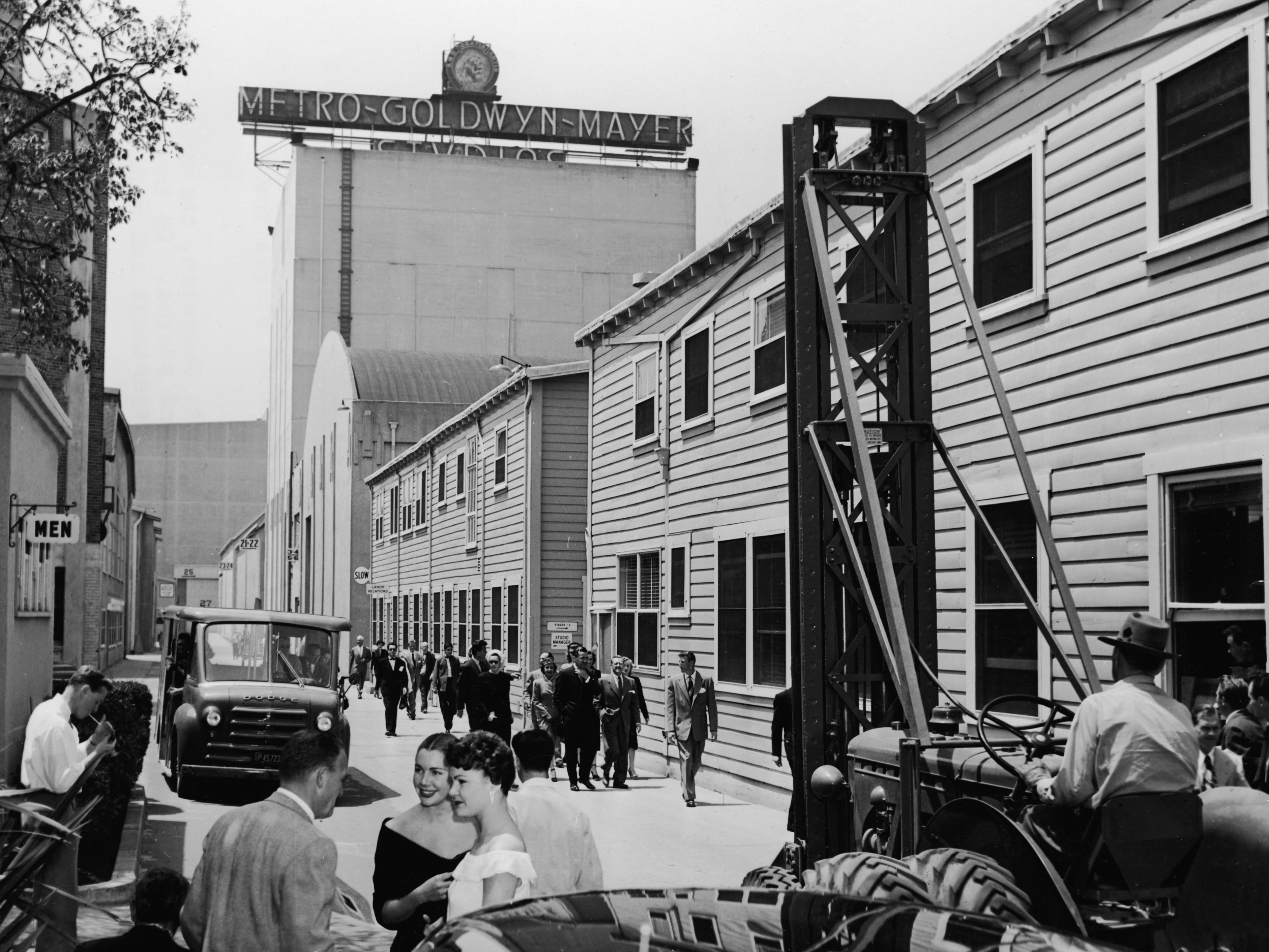 A man moves machinery and sets as groups of people walk down the main thoroughfare of MGM Studios in Hollywood, California, circa 1945