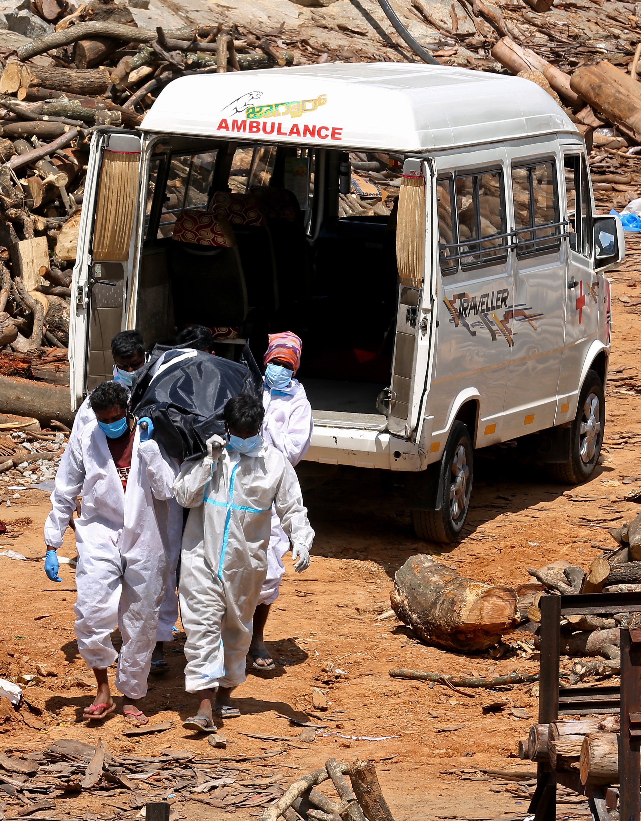 Cremation workers carry the body of Covid-19 victim for the funeral during mass cremation ground