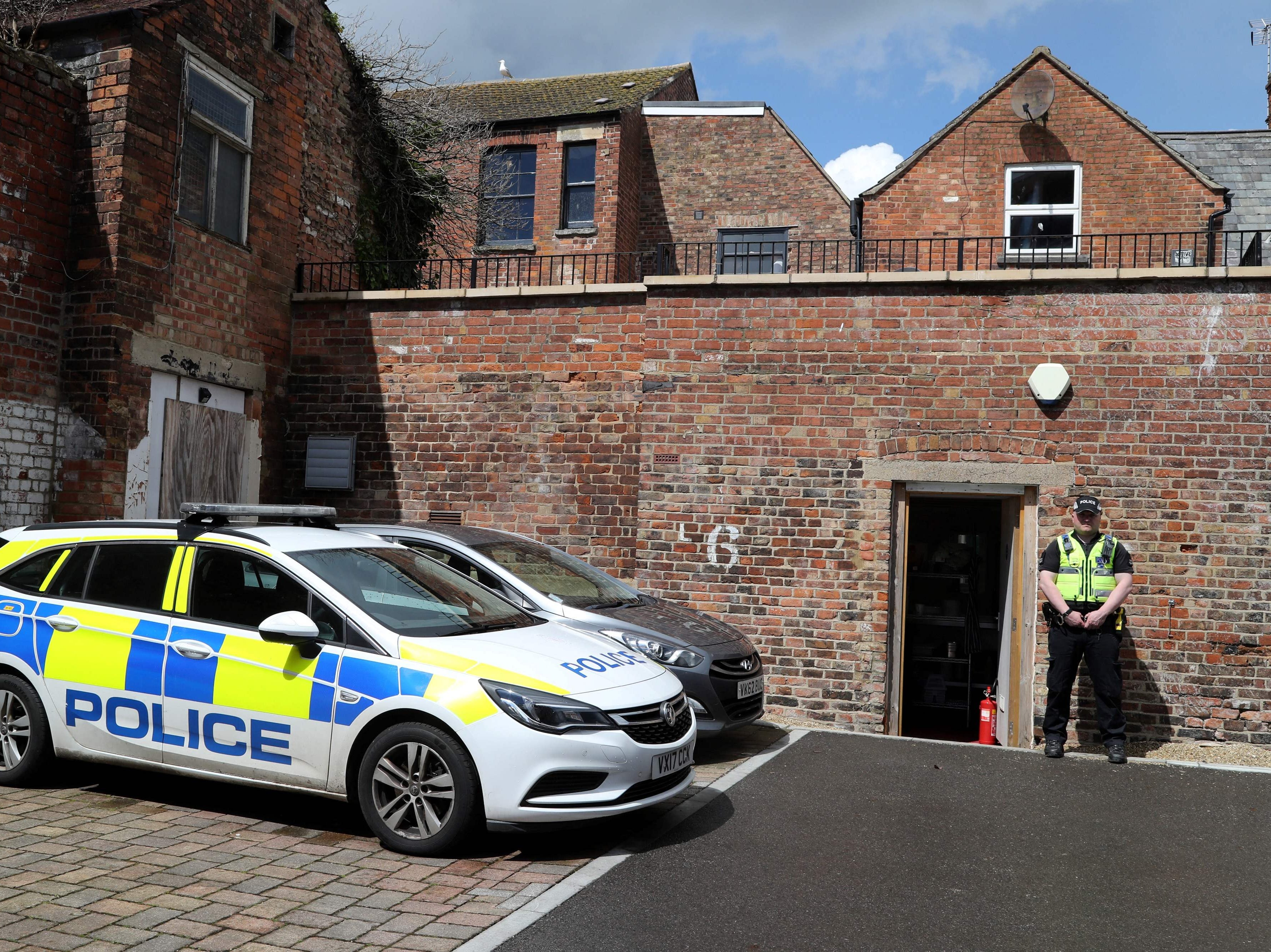 A police officer stands on duty at the rear entrance to The Clean Plate cafe in Gloucester