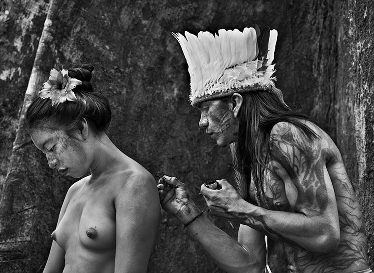 Keiá Yawanawá from the village of Mutum, paints the back of young Kanamashi, from the village of Amparo. The flower-shaped ornament in her hair is made of bird feathers. Rio Gregório Yawanawá Indigenous Territory, state of Acre, 2016