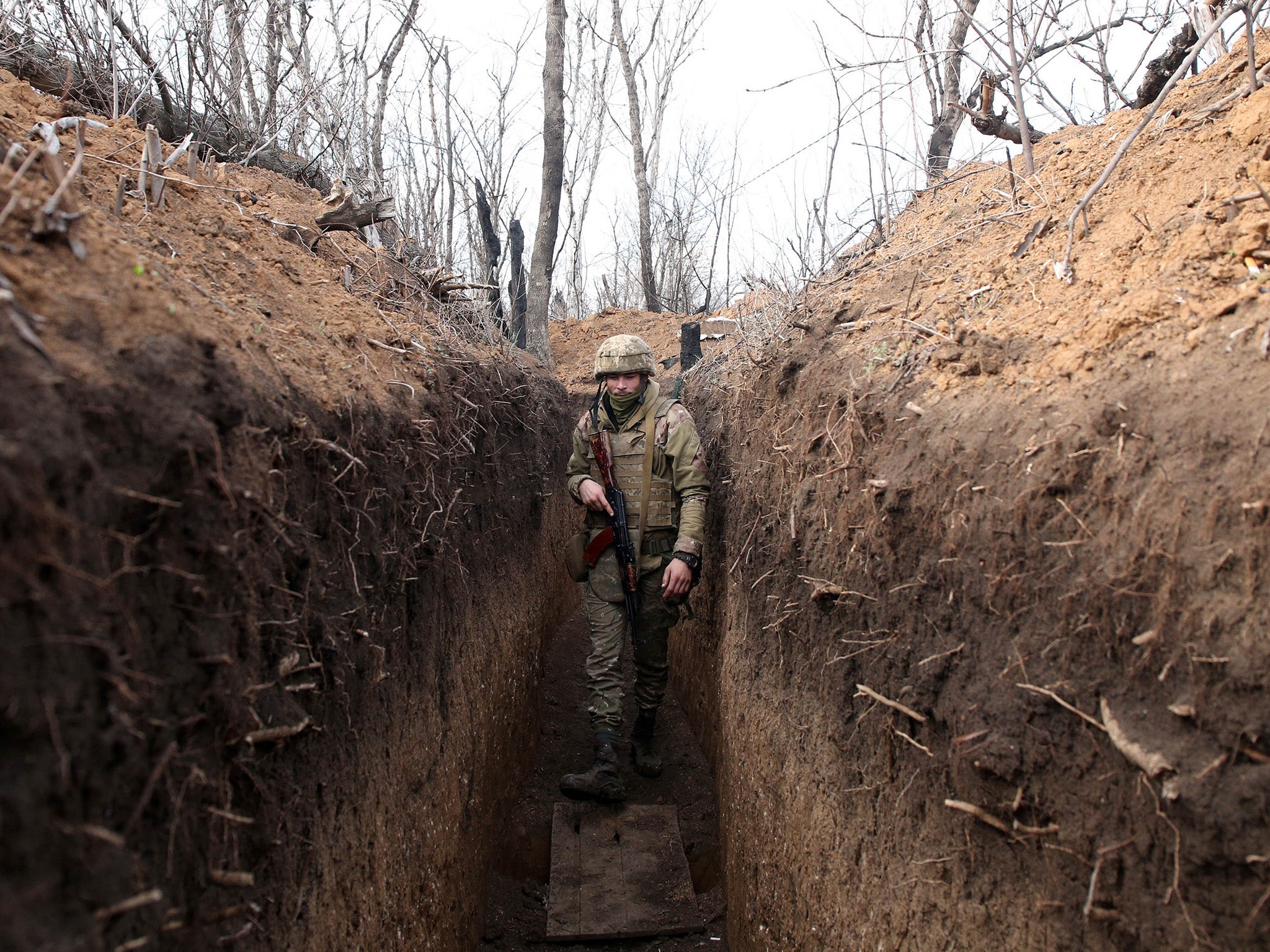 A Ukrainian serviceman walks along a trench on the front line with Russia-backed separatists near the town of Krasnohorivka, Donetsk province, in April