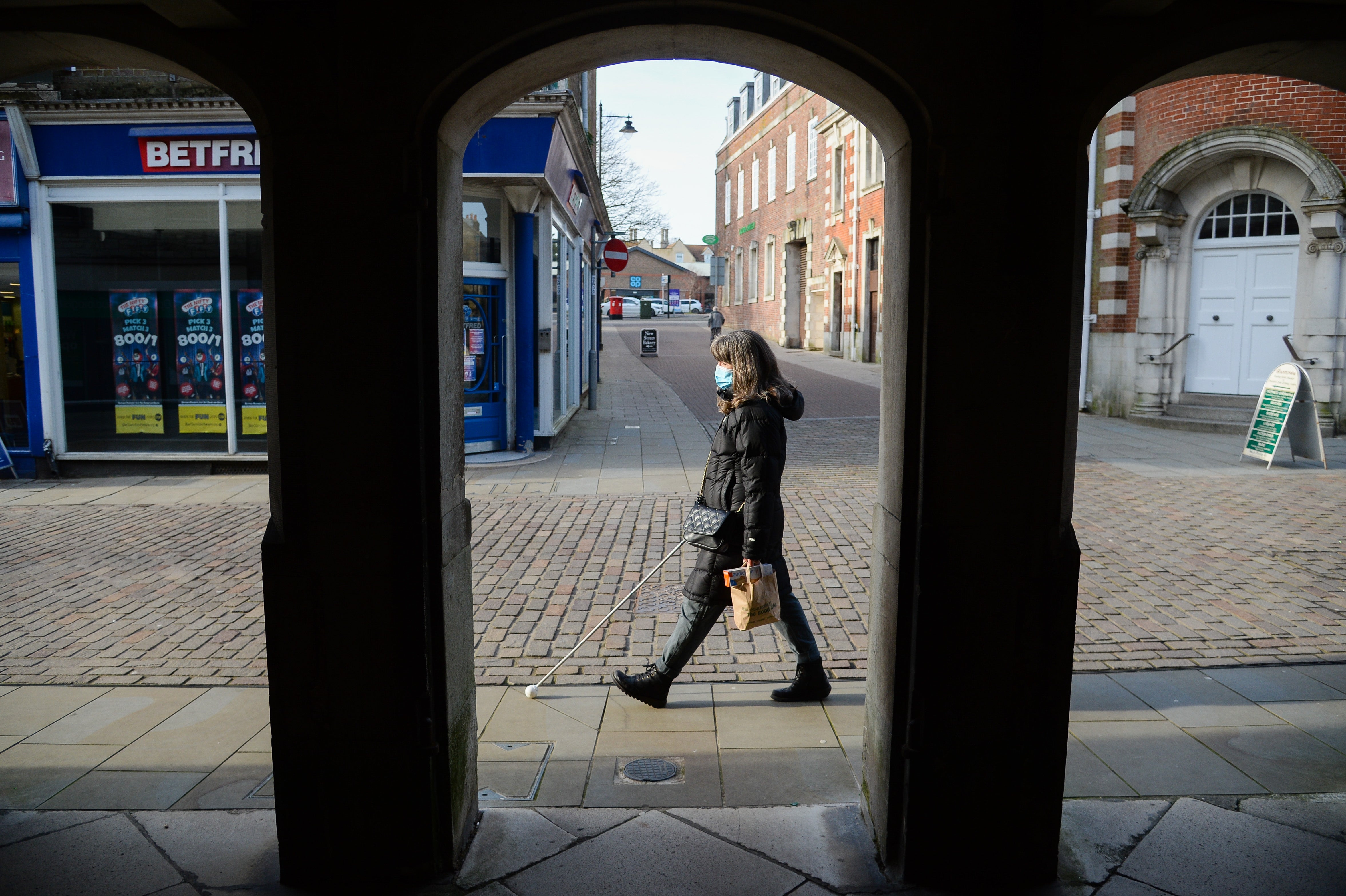 A blind woman walks along the high street in Dorchester, Dorset, during the Covid-19 lockdown in January