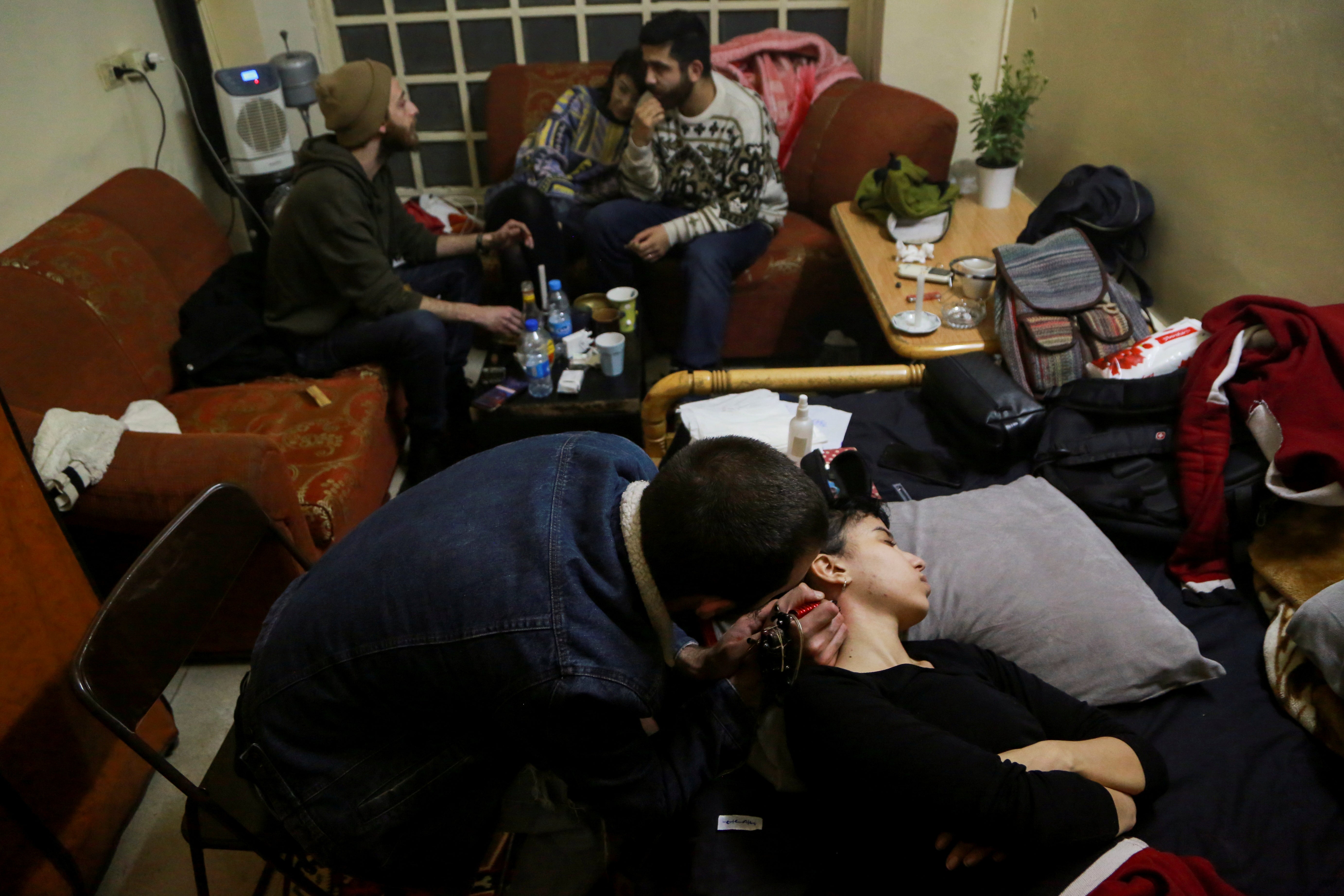 Aya, 24, a chef, rests as she gets a tattoo on her neck at her friend's house