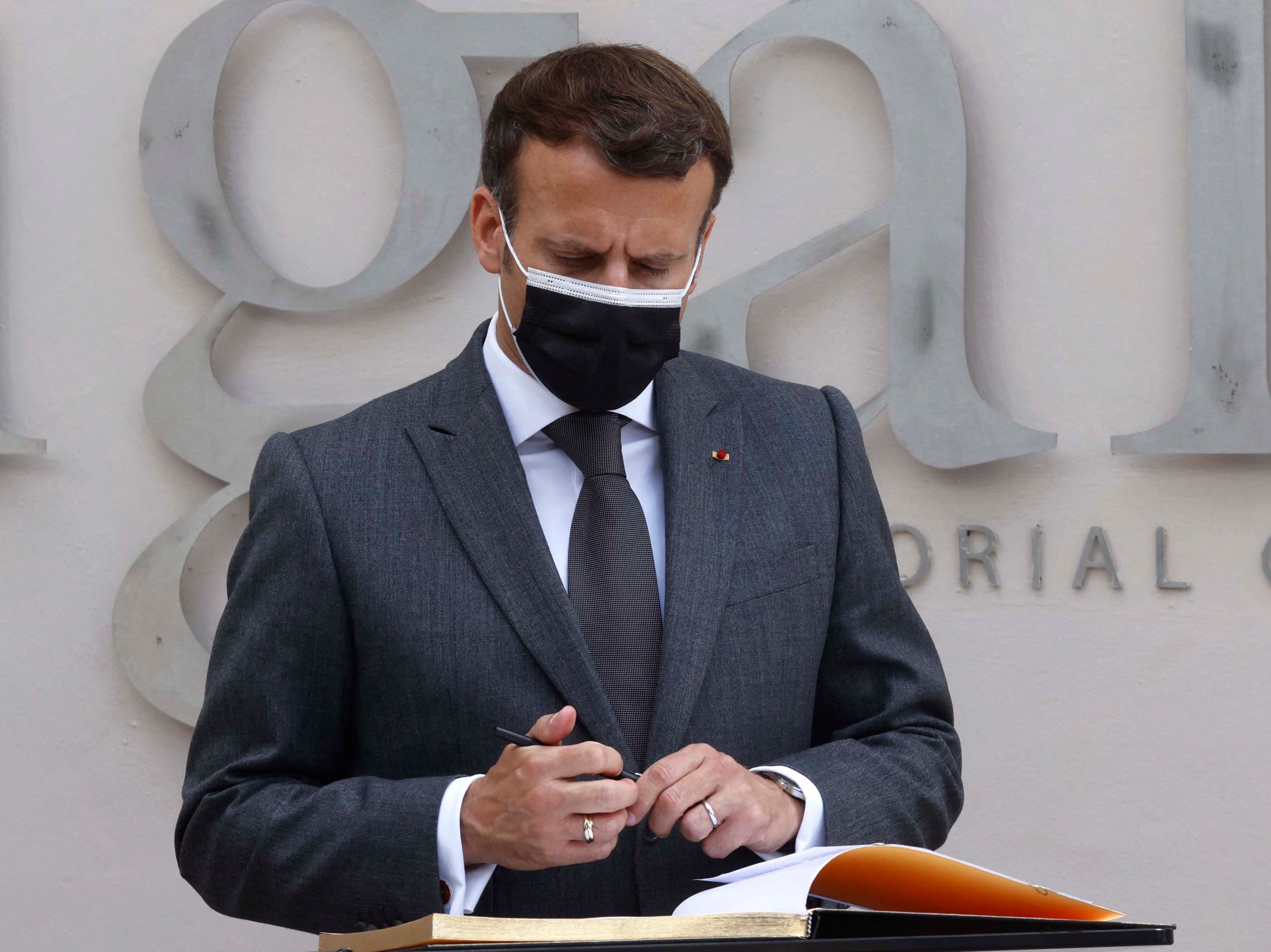 Emmanuel Macron signs the memorial book during his visit to the Kigali Genocide Memorial, where some 250,000 victims of the massacres are buried