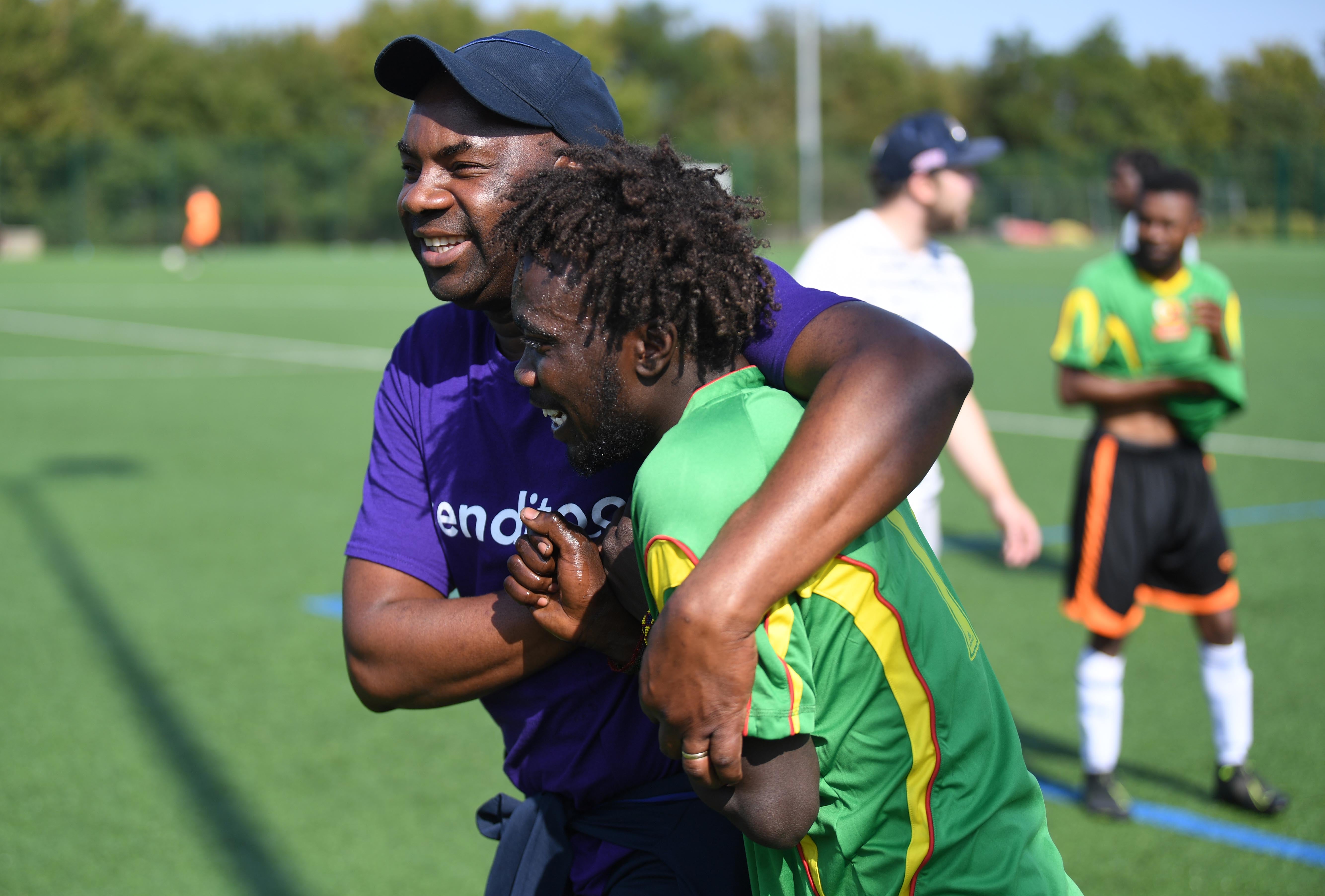 Sanctuary Strikers Football Club founder Tomson Chalk hugs player Adam Hussai during a friendly match against Reading Reserves