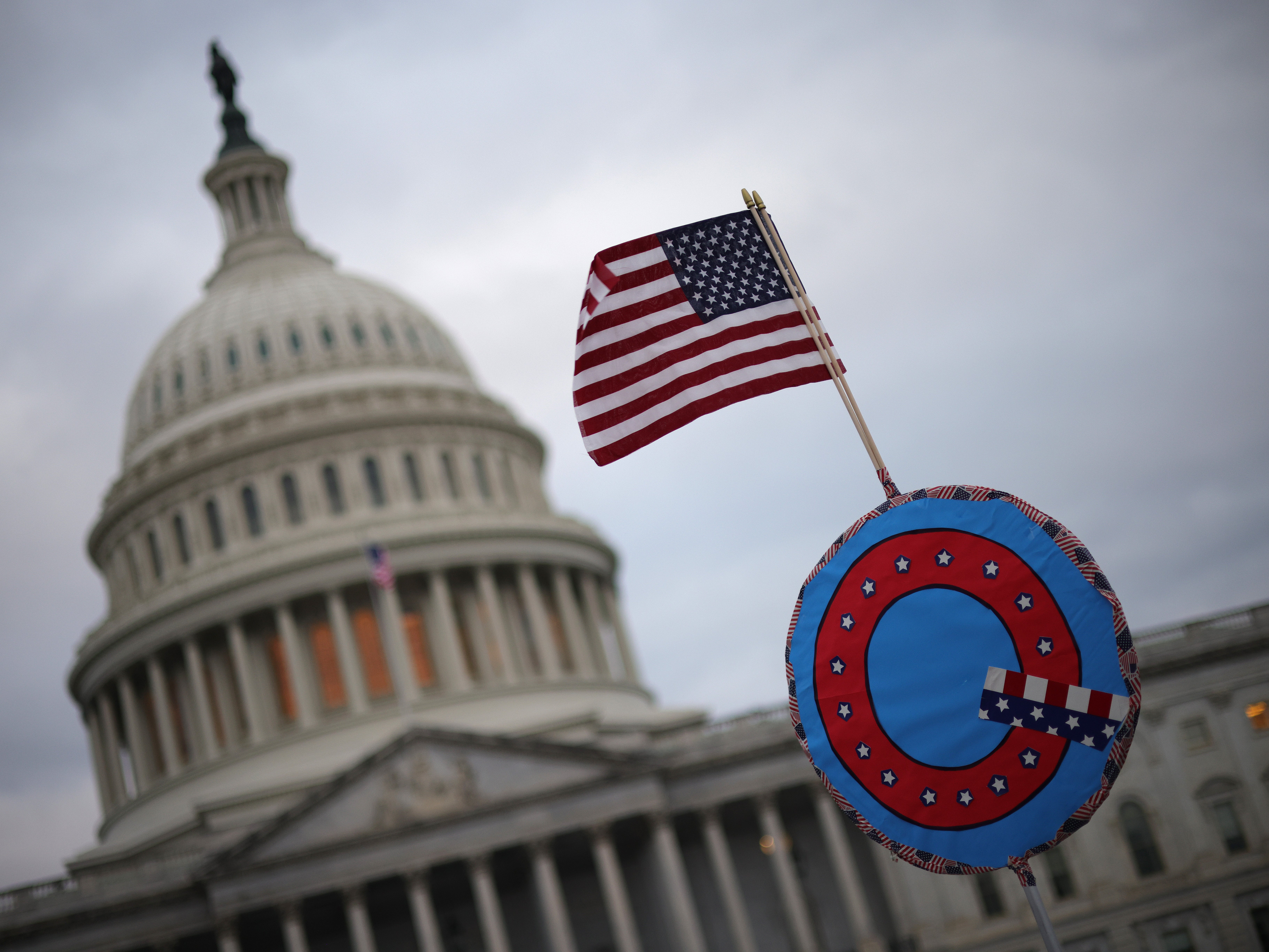 Trump supporters fly a US flag with a symbol denoting QAnon as they gather outside the US Capitol on 6 January