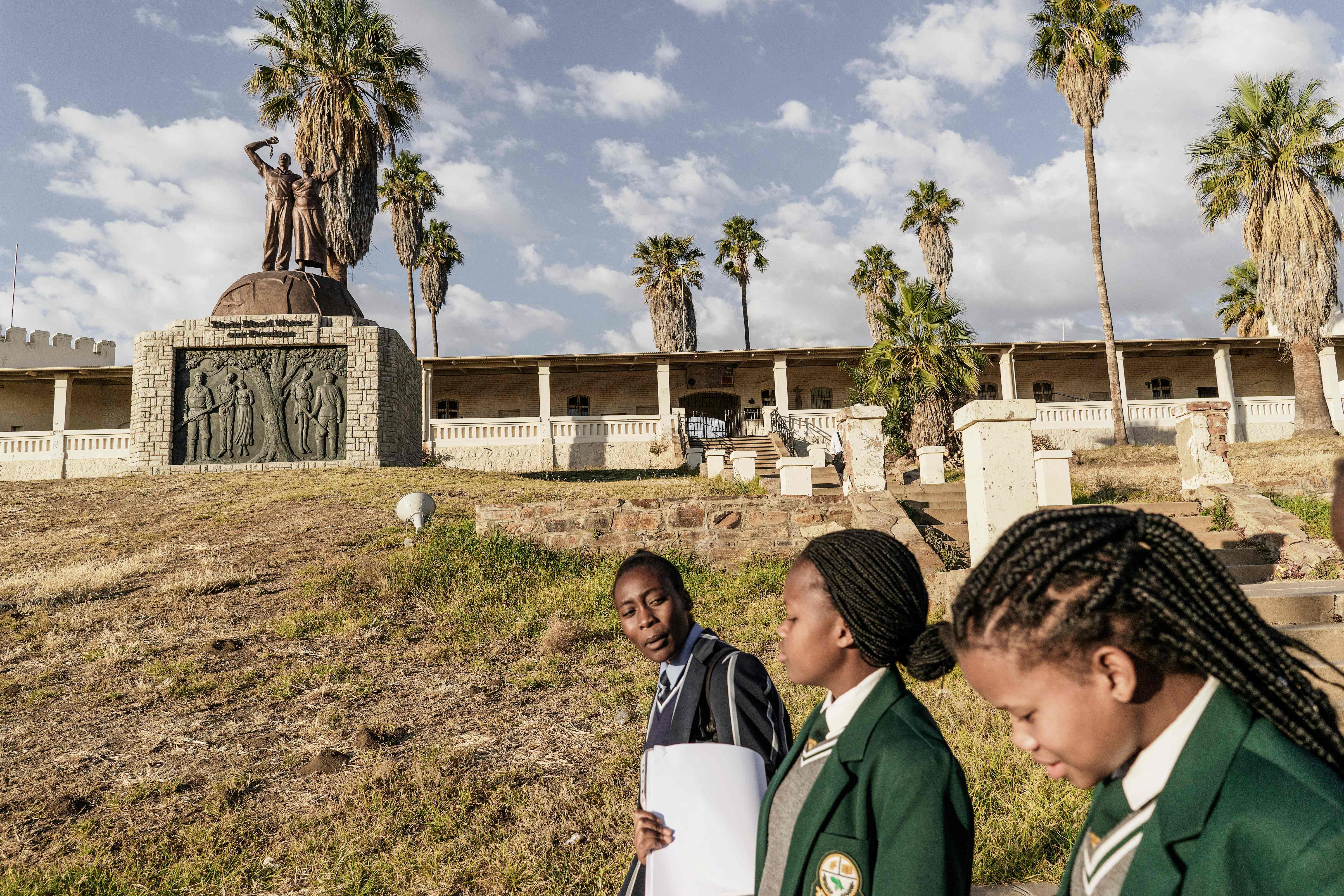 Namibian schoolgirls walking by a memorial to the victims of the genocide committed by German forces