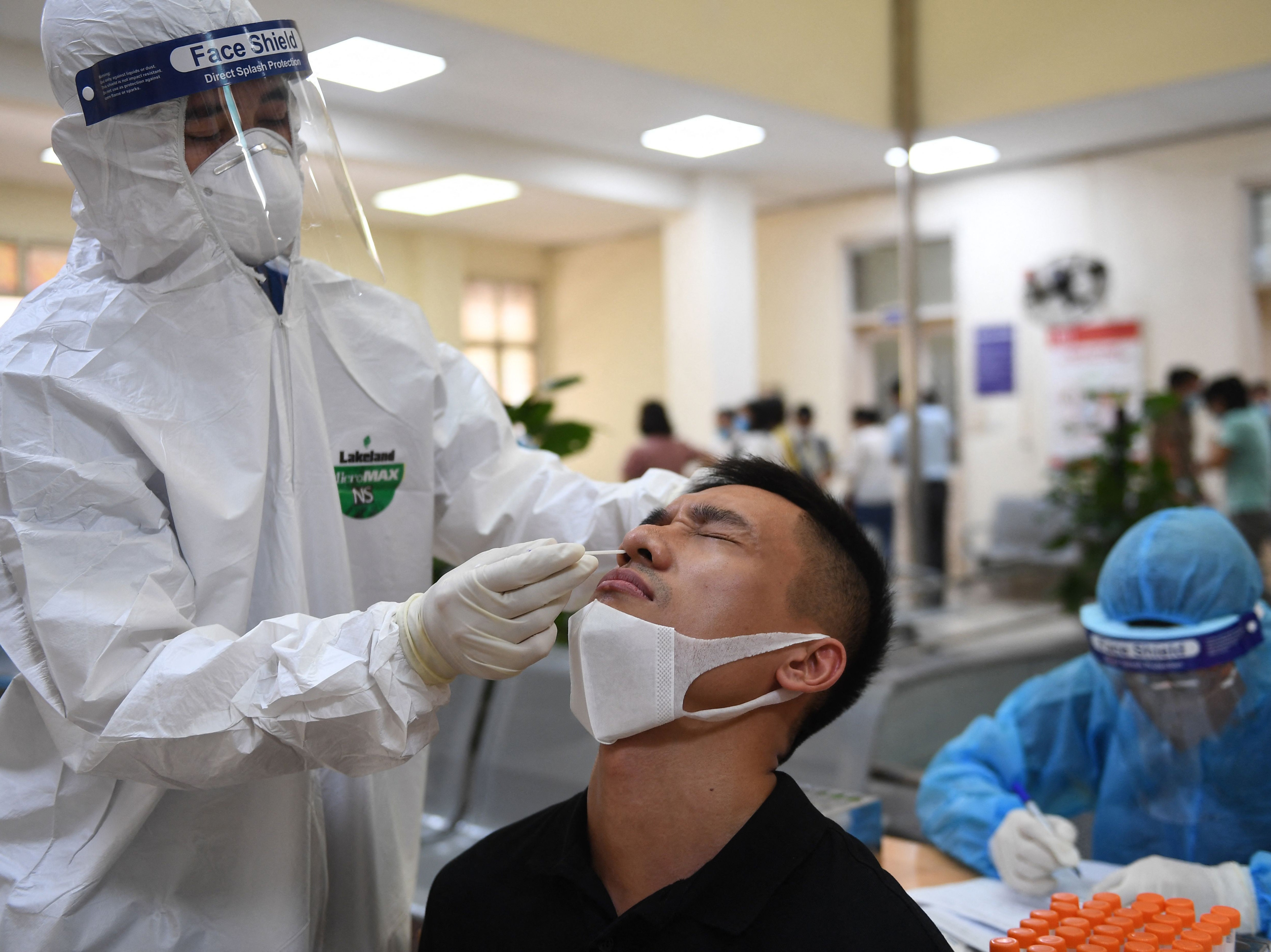 A health worker conducts a Covid-19 test on a man at Hanoi’s Center for Disease Control and Prevention on 22 May