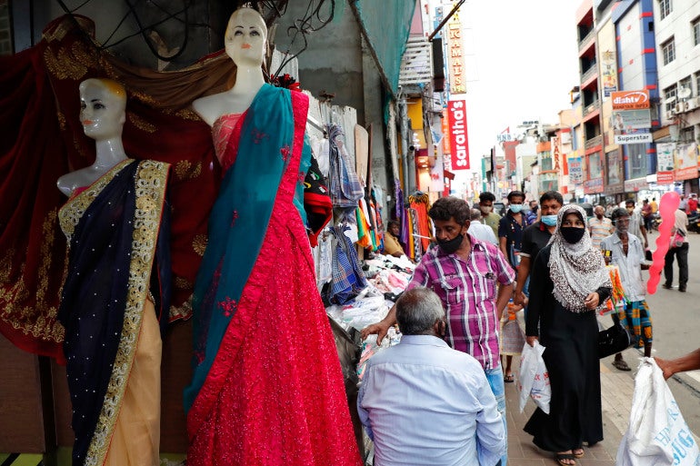 A Sri Lankan Muslim woman, right in black attire, walks in a busy street of Colombo, Sri Lanka, Saturday, March 13, 2021. Sri Lanka has announced plans to ban the wearing of burqas and said it would close more than 1,000 Islamic schools known as madrassas