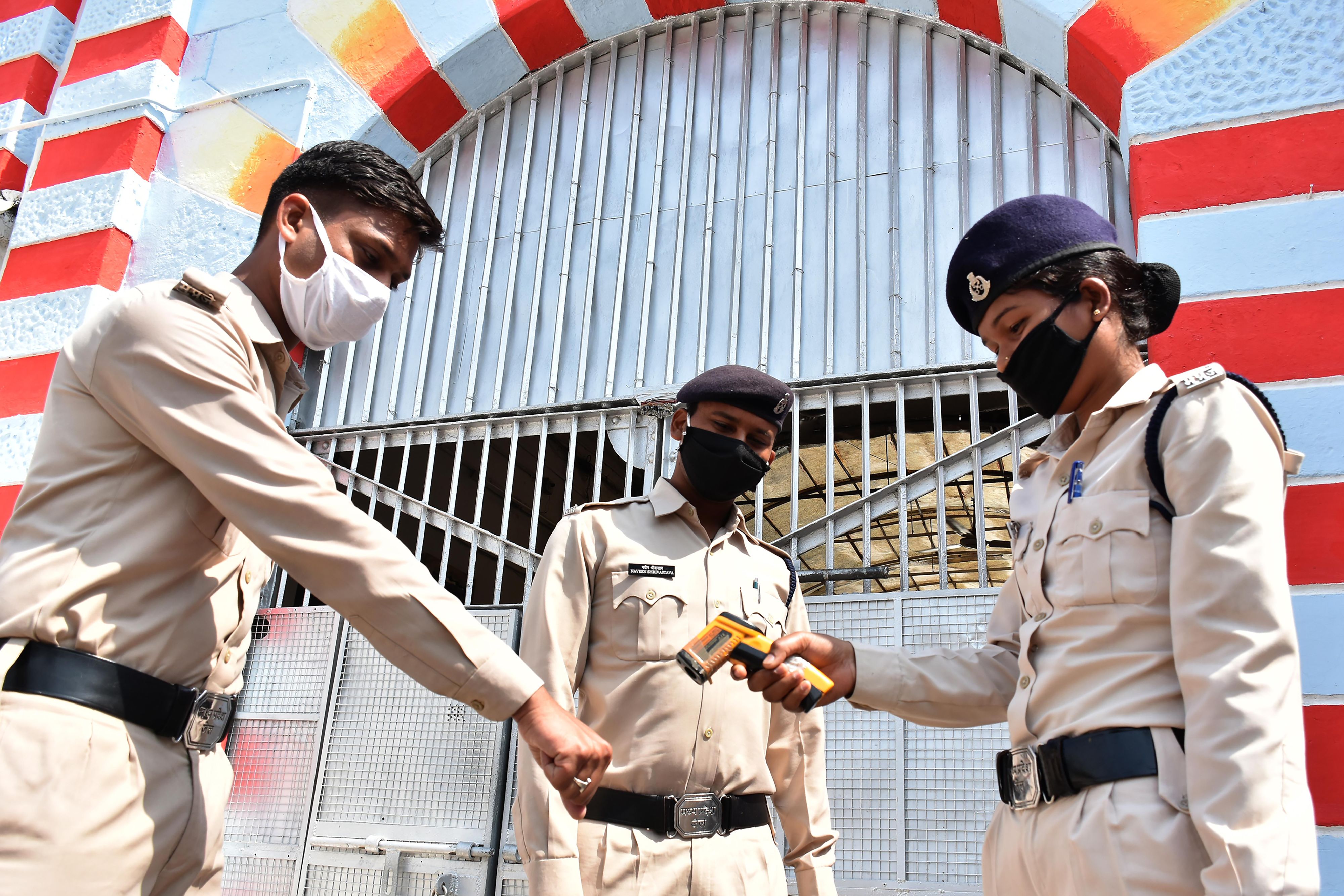 A security personnel at Netaji Subhash Chandra Bose central jail in Madhya Pradesh checks the temperature of duty policemen