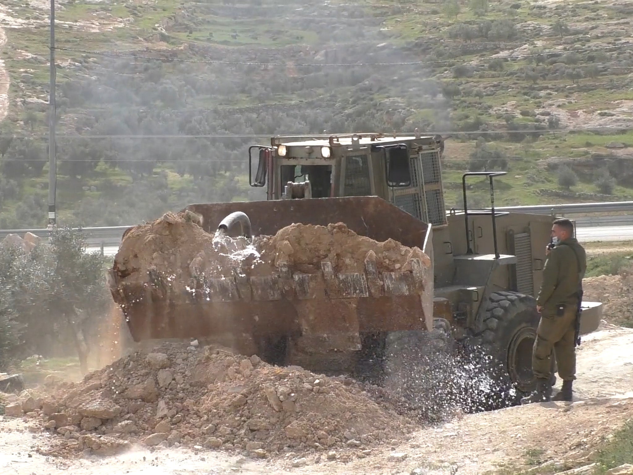 Israeli military officers destroy a water line serving 40 families and block the access road to the community of She’b al-Balem, South Hebron Hills