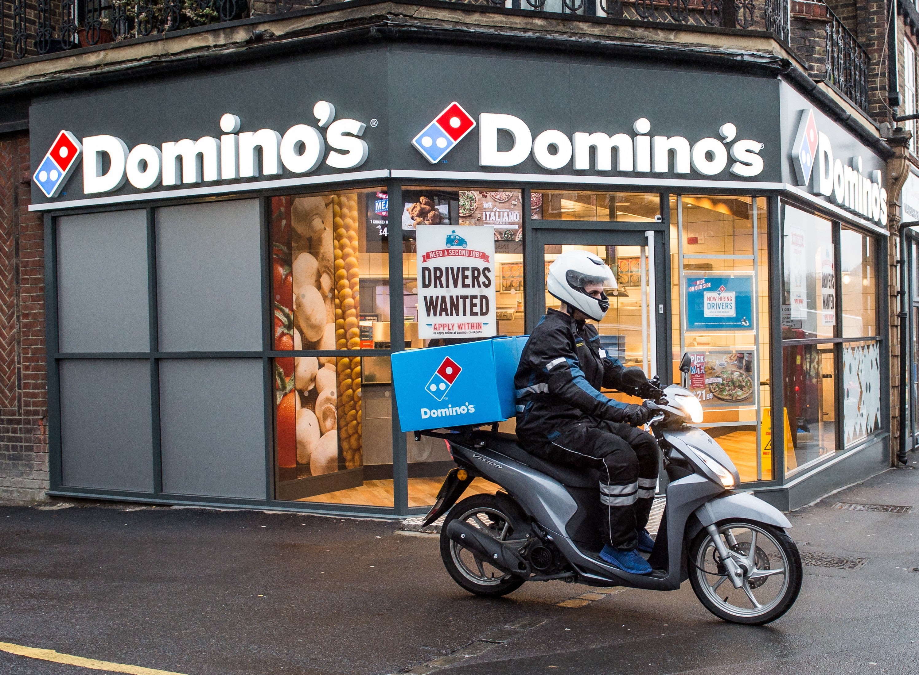 A delivery rider outside a branch of Domino’s Pizza