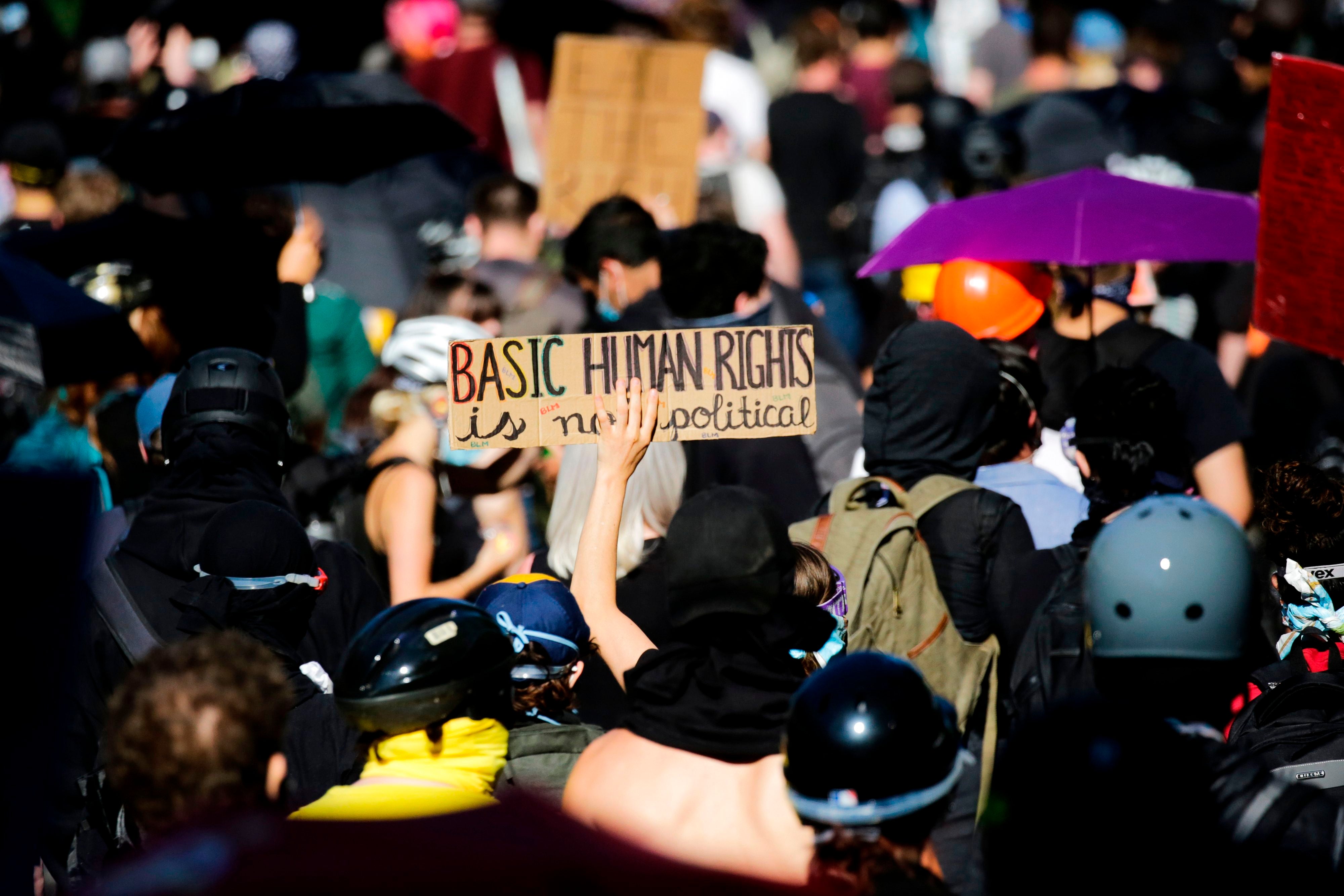 Protester hold signs as they confronts a line of police at the former location of the Capitol Hill Organized Protest (CHOP) following a “Youth Day of Action and Solidarity with Portland” demonstration in Seattle, Washington on July 25, 2020.