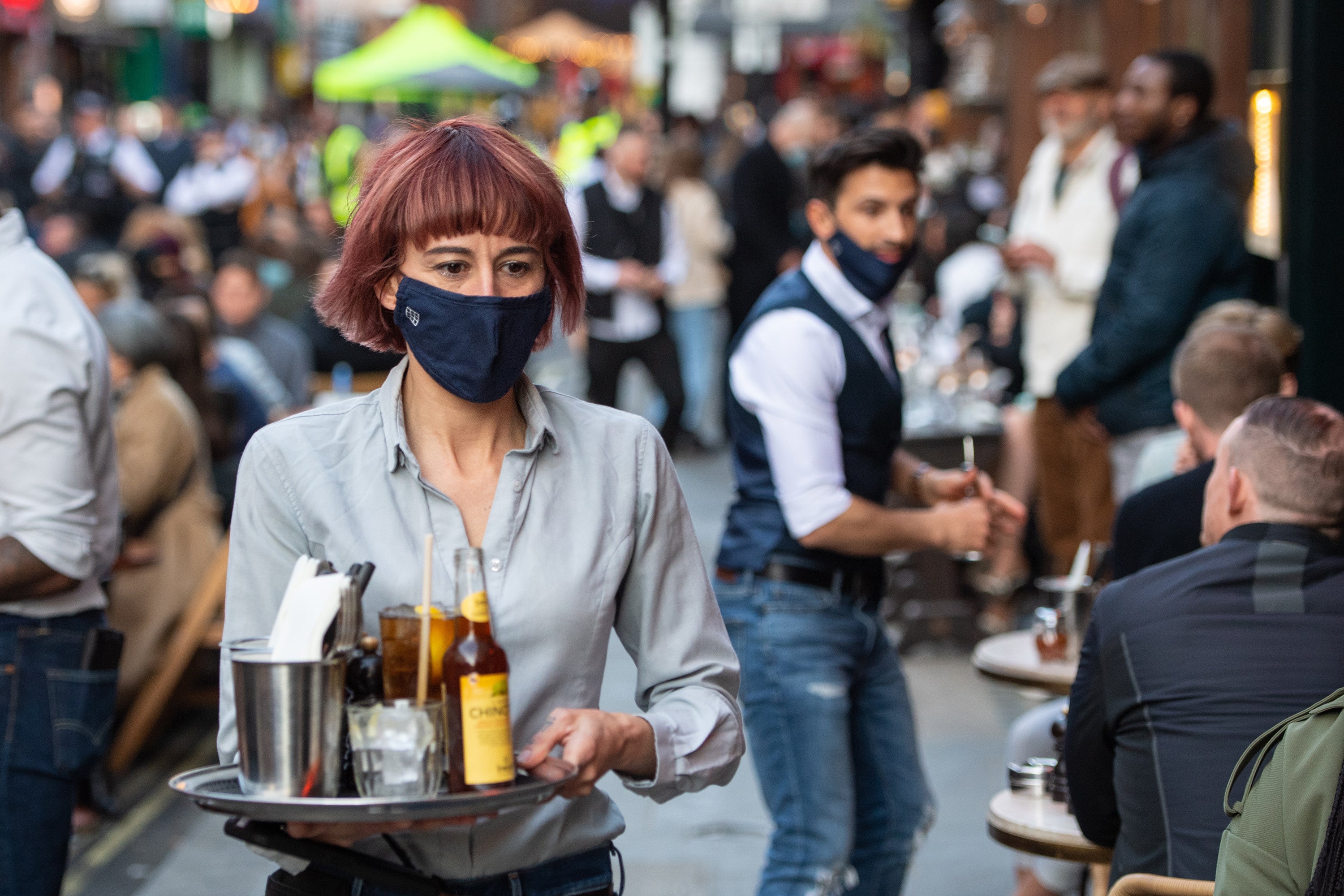 Waiters serve people eating and drinking at outside tables