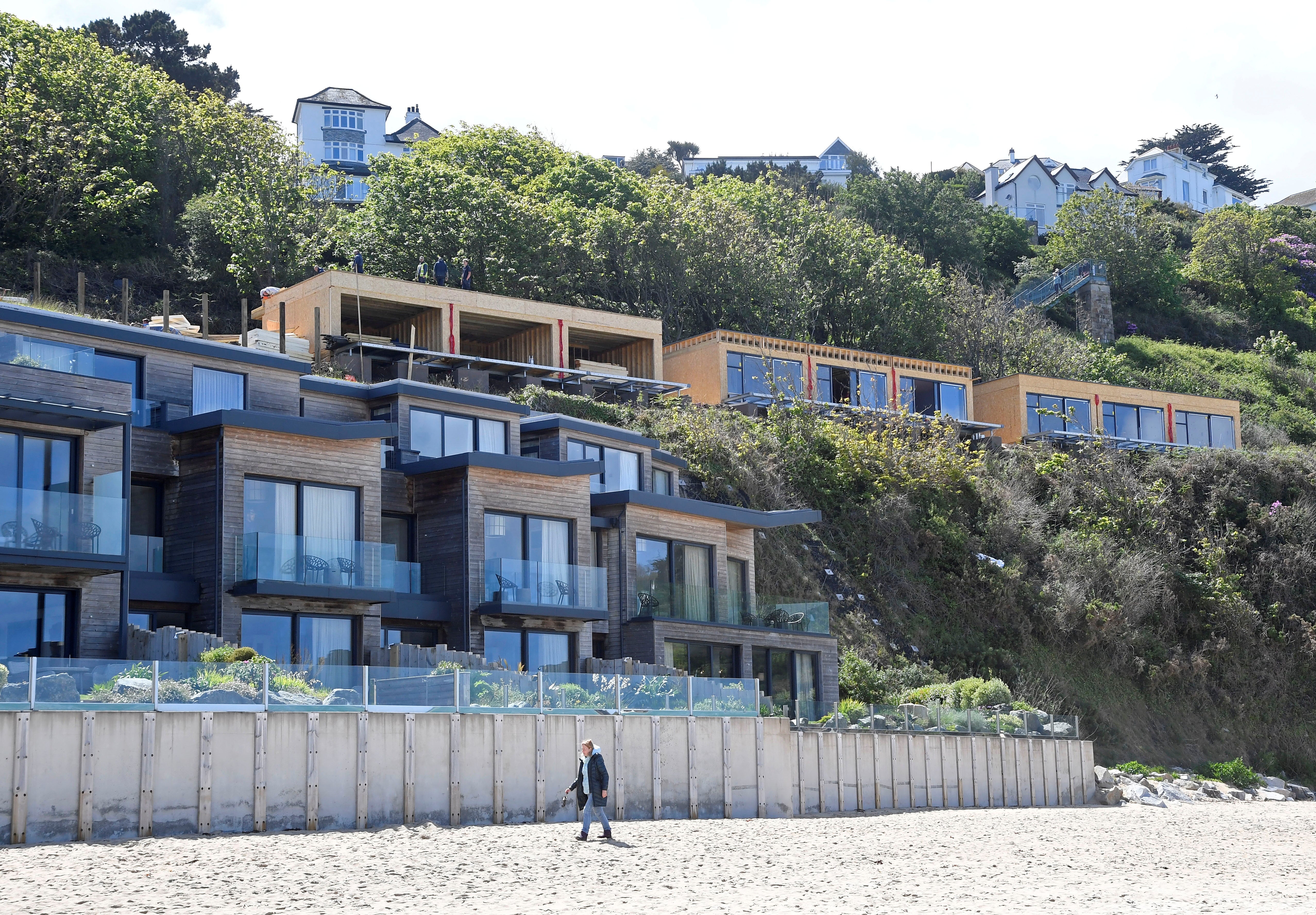 A woman walks on the beach beside the Carbis Bay hotel, where an in-person G7 summit of global leaders is due to take place