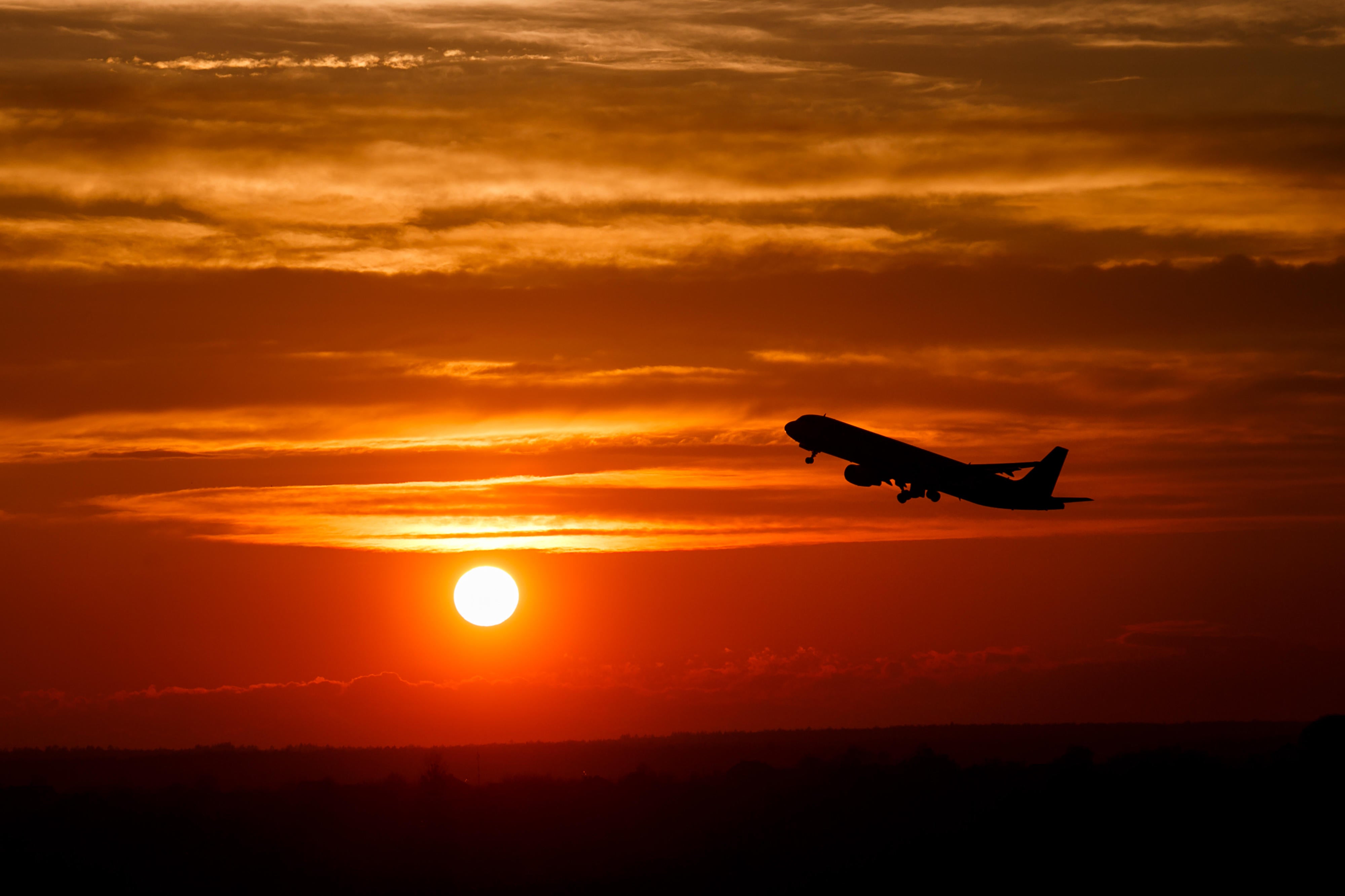 Airplane taking off in sunset sky