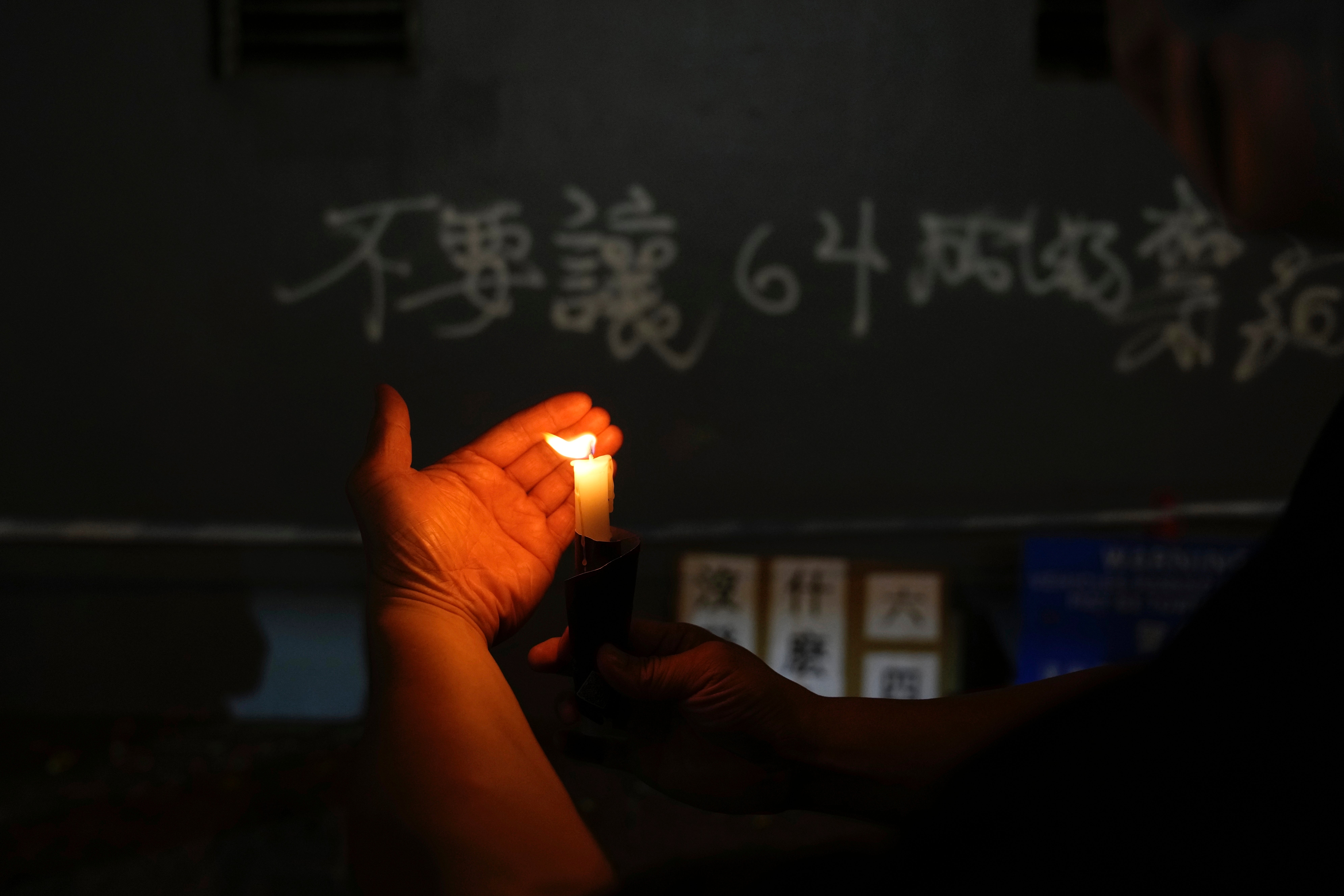 A protester lights candles to mark the anniversary of the military crackdown on a pro-democracy student movement in Beijing, outside the Victoria Park in Hong Kong, Friday, 4 June, 2021