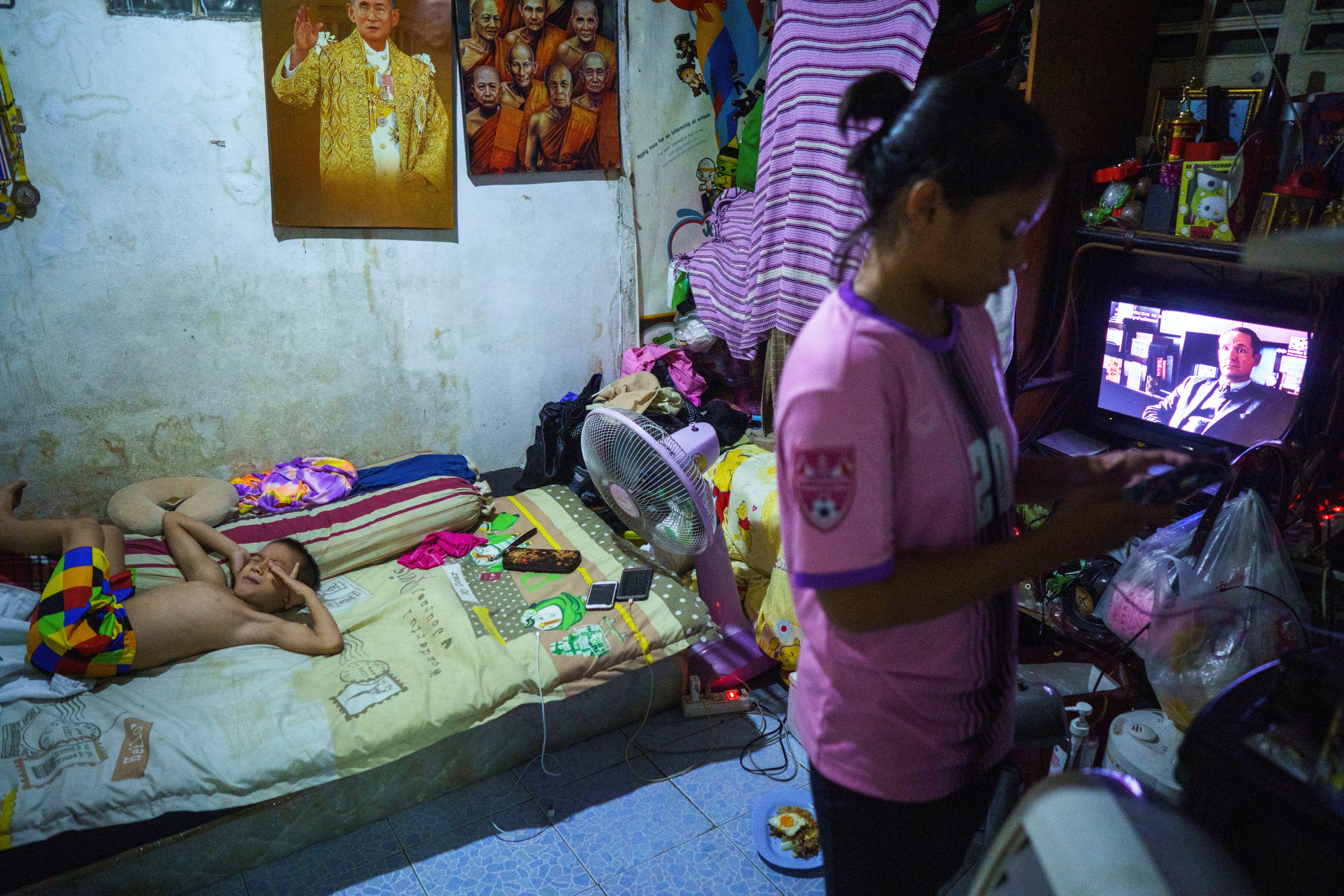 Tata tries to sleep as his sister uses a mobile phone at their home inside a gym in Bangkok