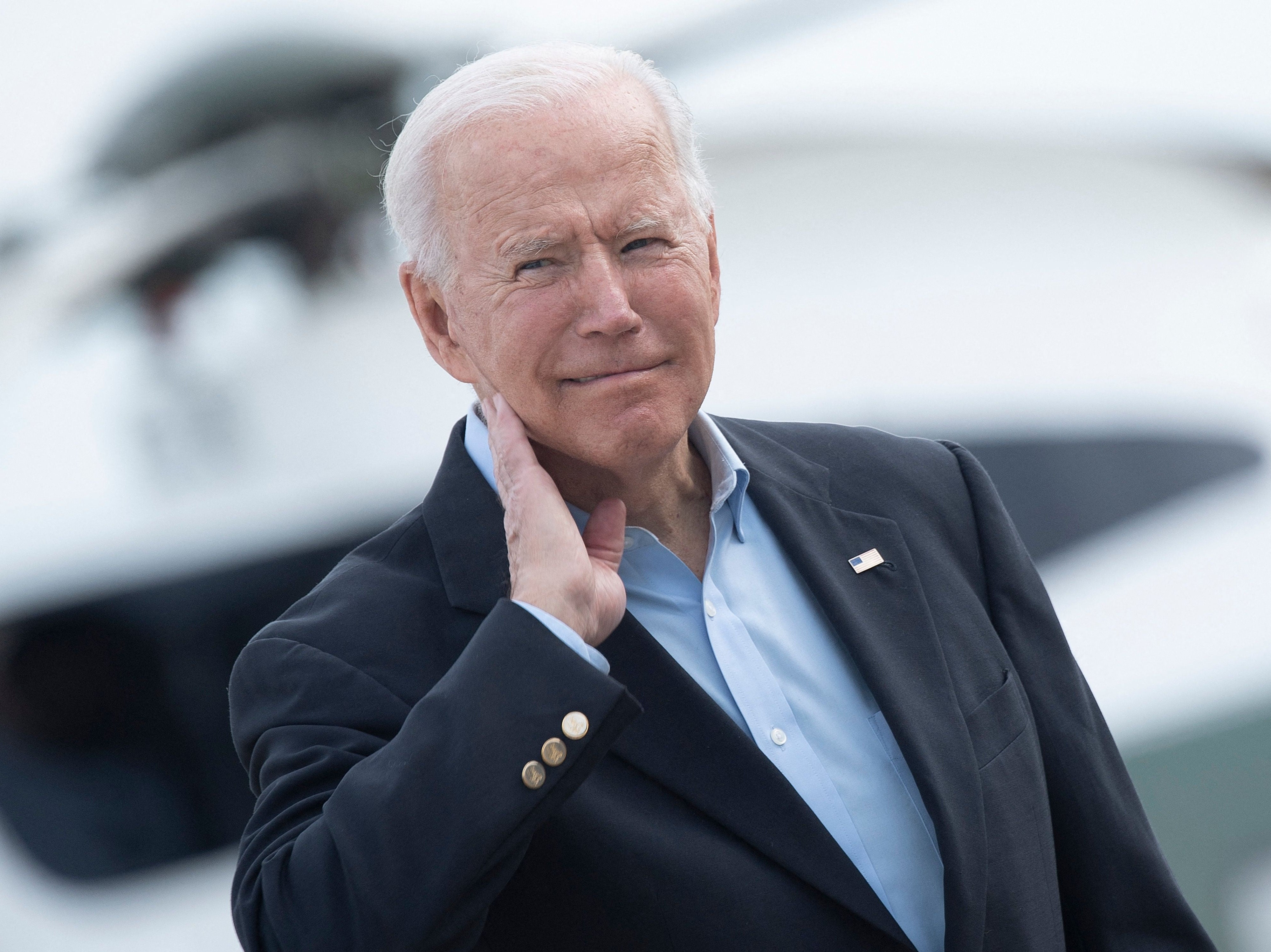 US President Joe Biden wipes his neck after a cicada landed on him while boarding Air Force One at Andrews Air Force Base