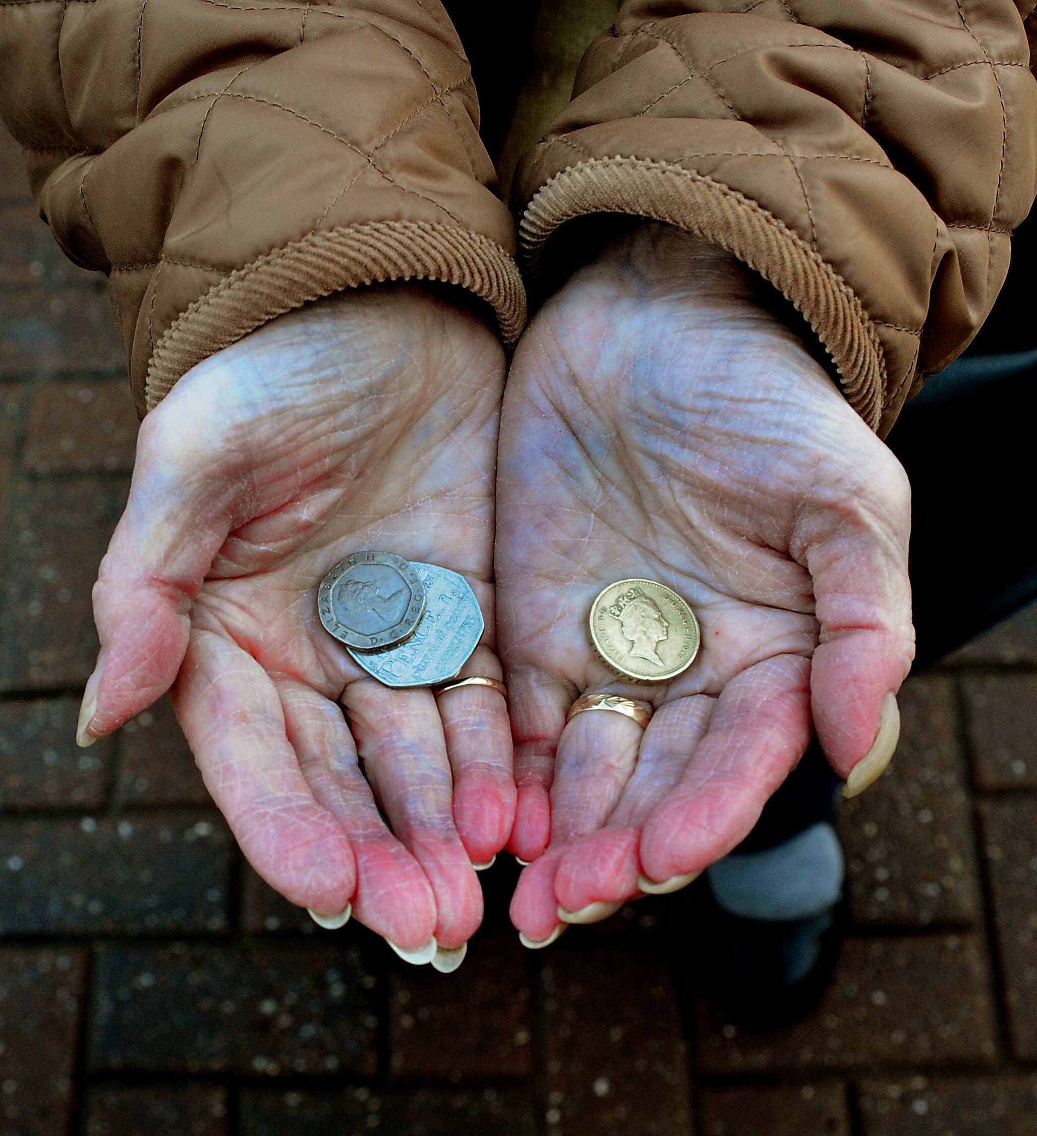 An elderly person holding a few coins