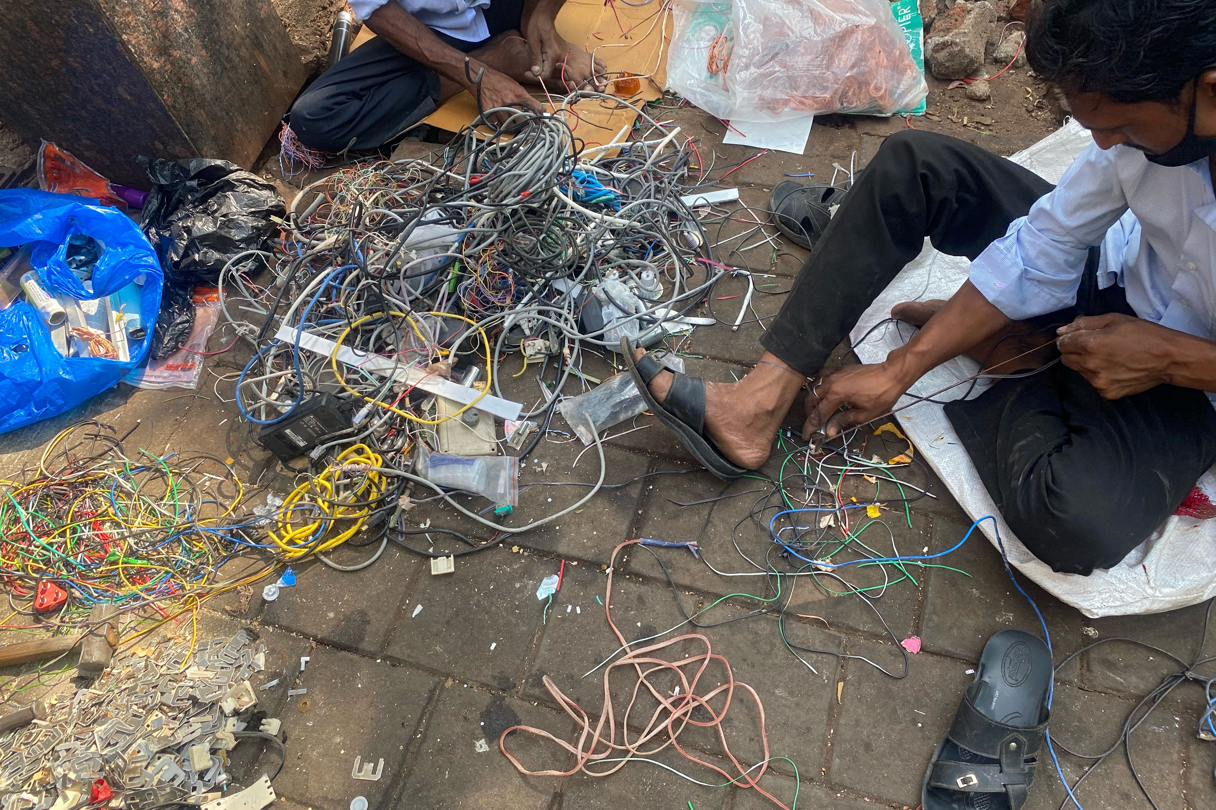 Scrap dealers retrieve copper from discarded electric and computer cables to sell at a roadside stall in Mumbai