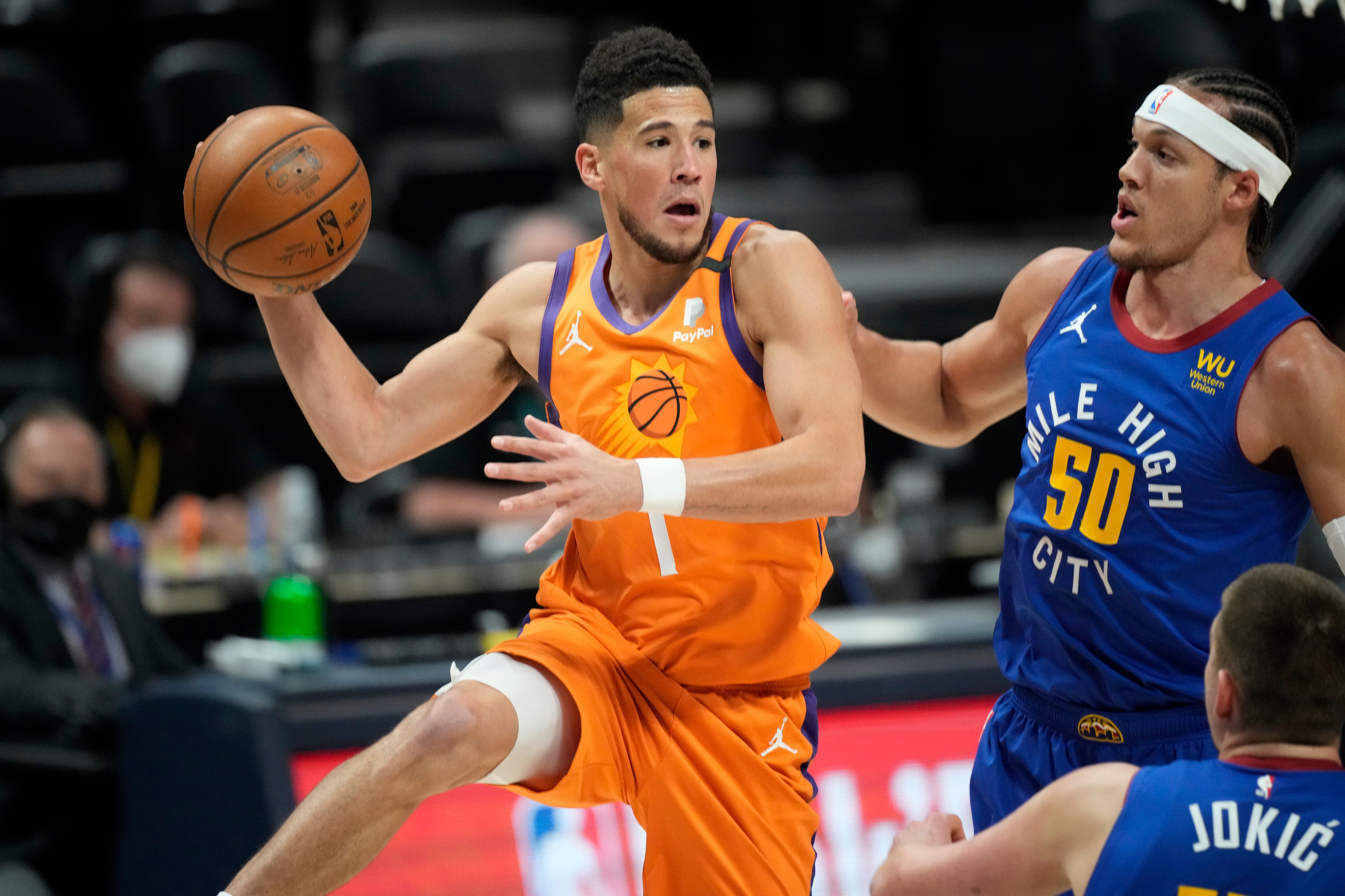 Phoenix Suns guard Devin Booker, left, passes the ball as Denver Nuggets forward Aaron Gordon defends