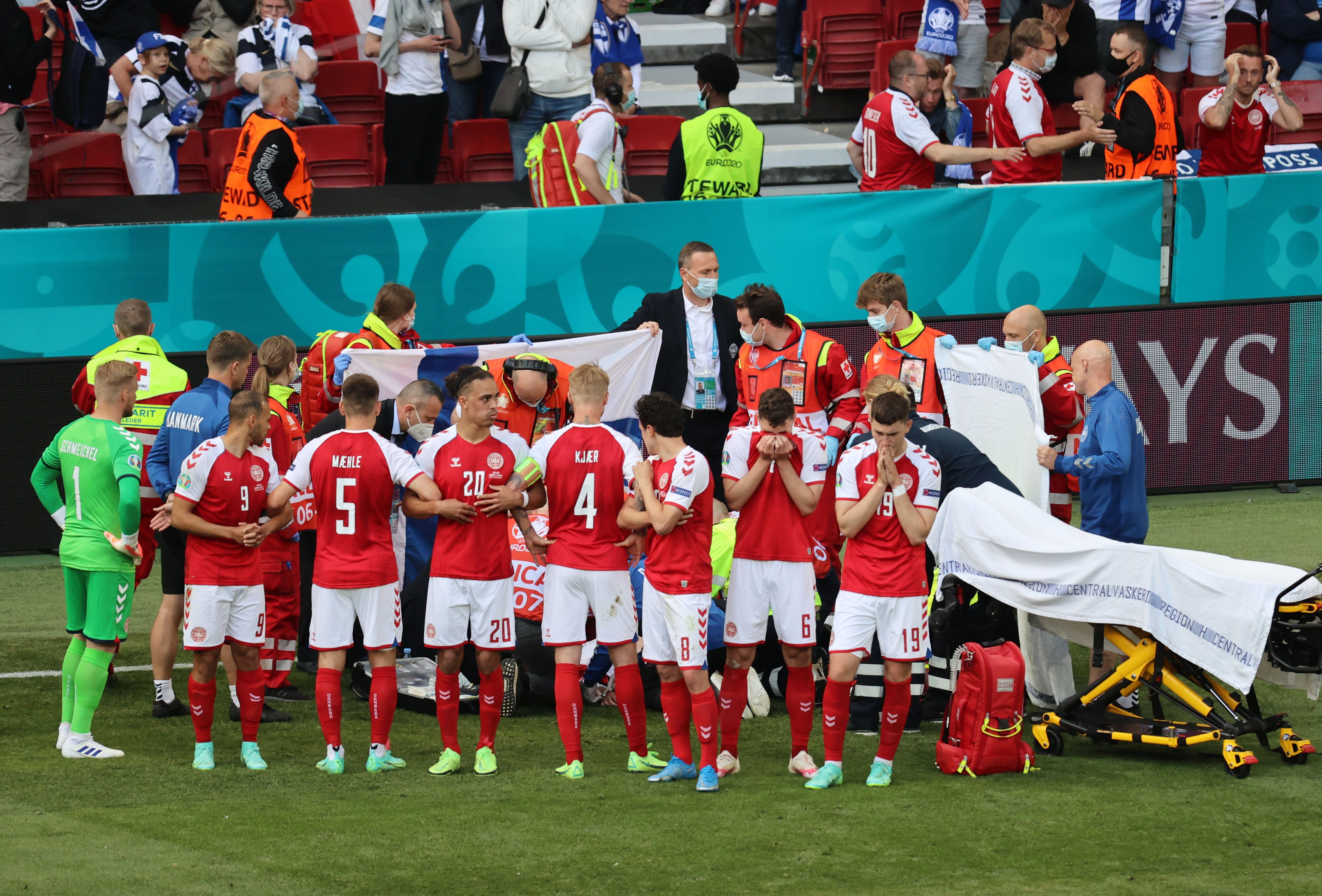 Denmark players shield Christian Eriksen while he receives medical attention