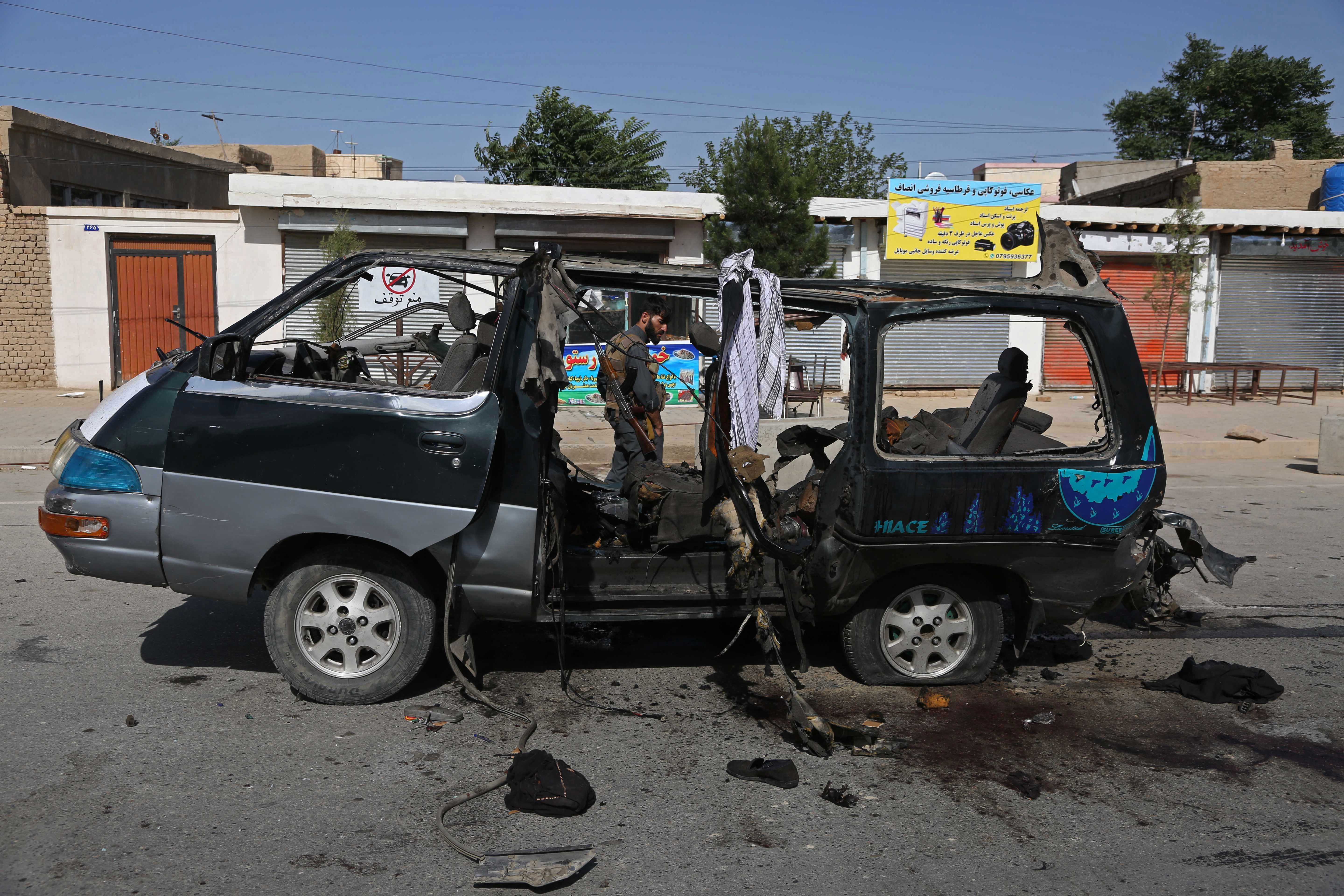 A security personnel stands next to a damaged vehicle at the site of an explosion in Kabul on June 3, 2021. At least seven people have been killed in two new attacks on minivans.