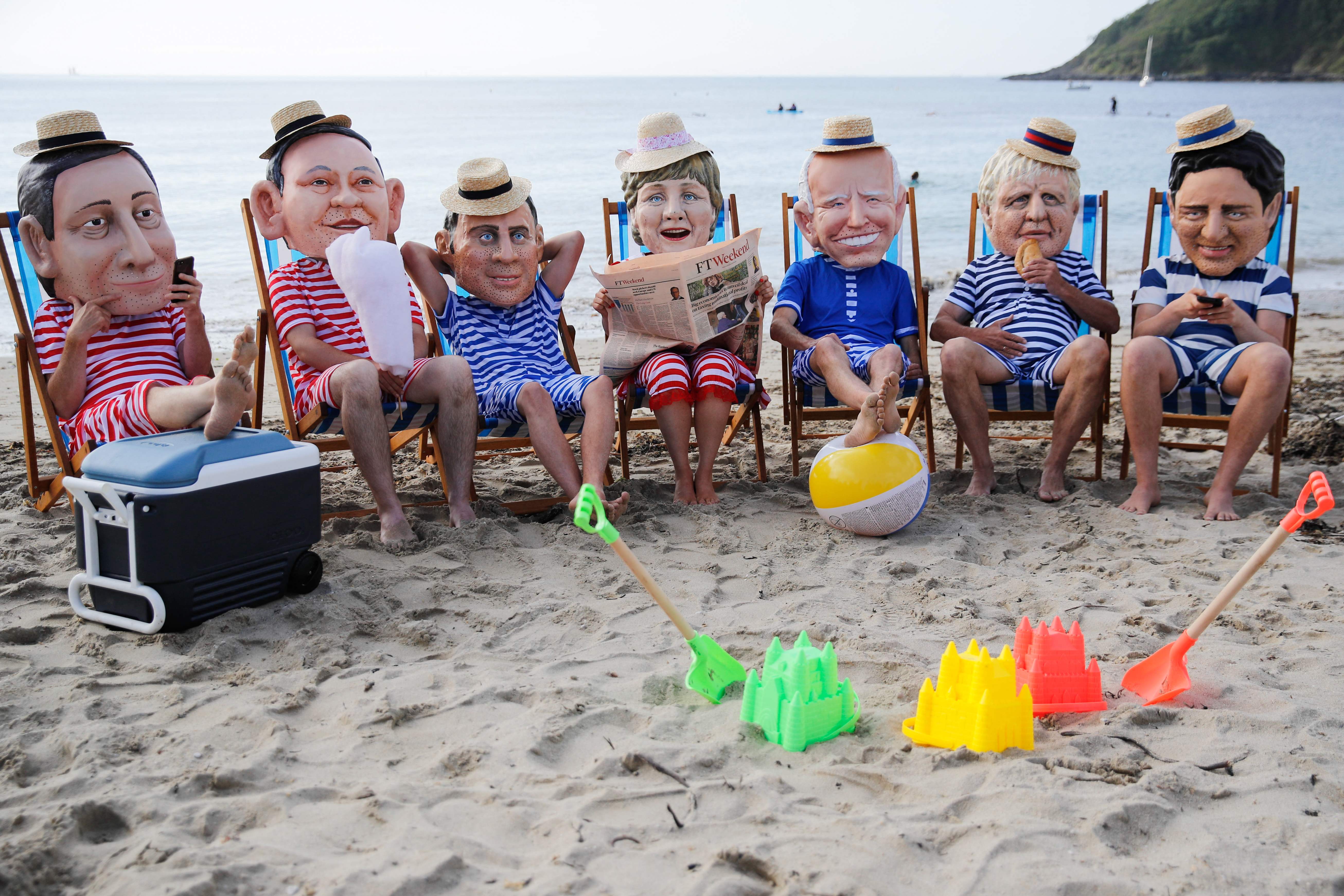 Oxfam activists wearing papier mache heads representing G7 leaders perform during a protest near Falmouth