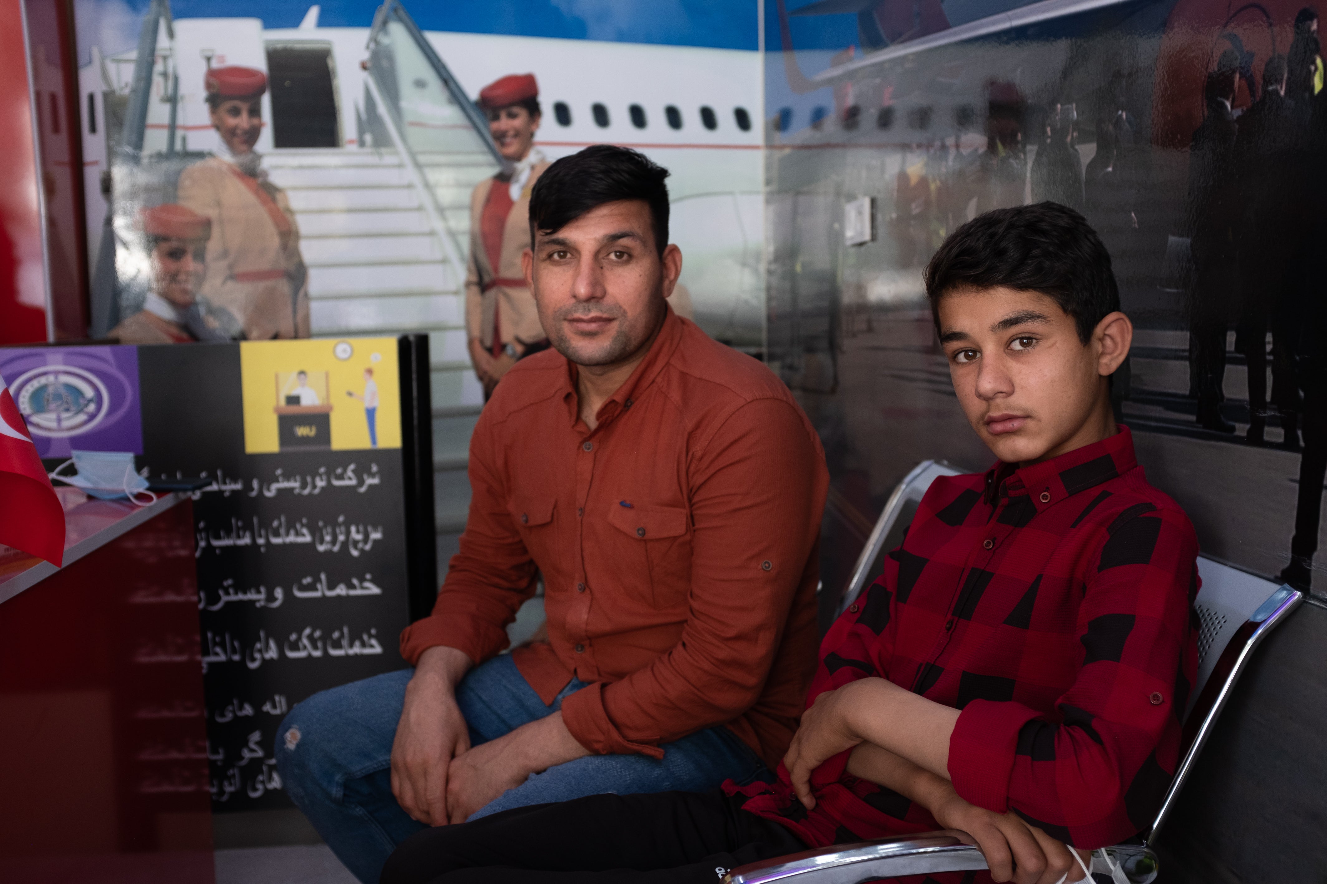 Mohammedollah Qandari and his 13-year-old son, Obeidollah, in a travel agency in the Zeytinburnu district of Istanbul