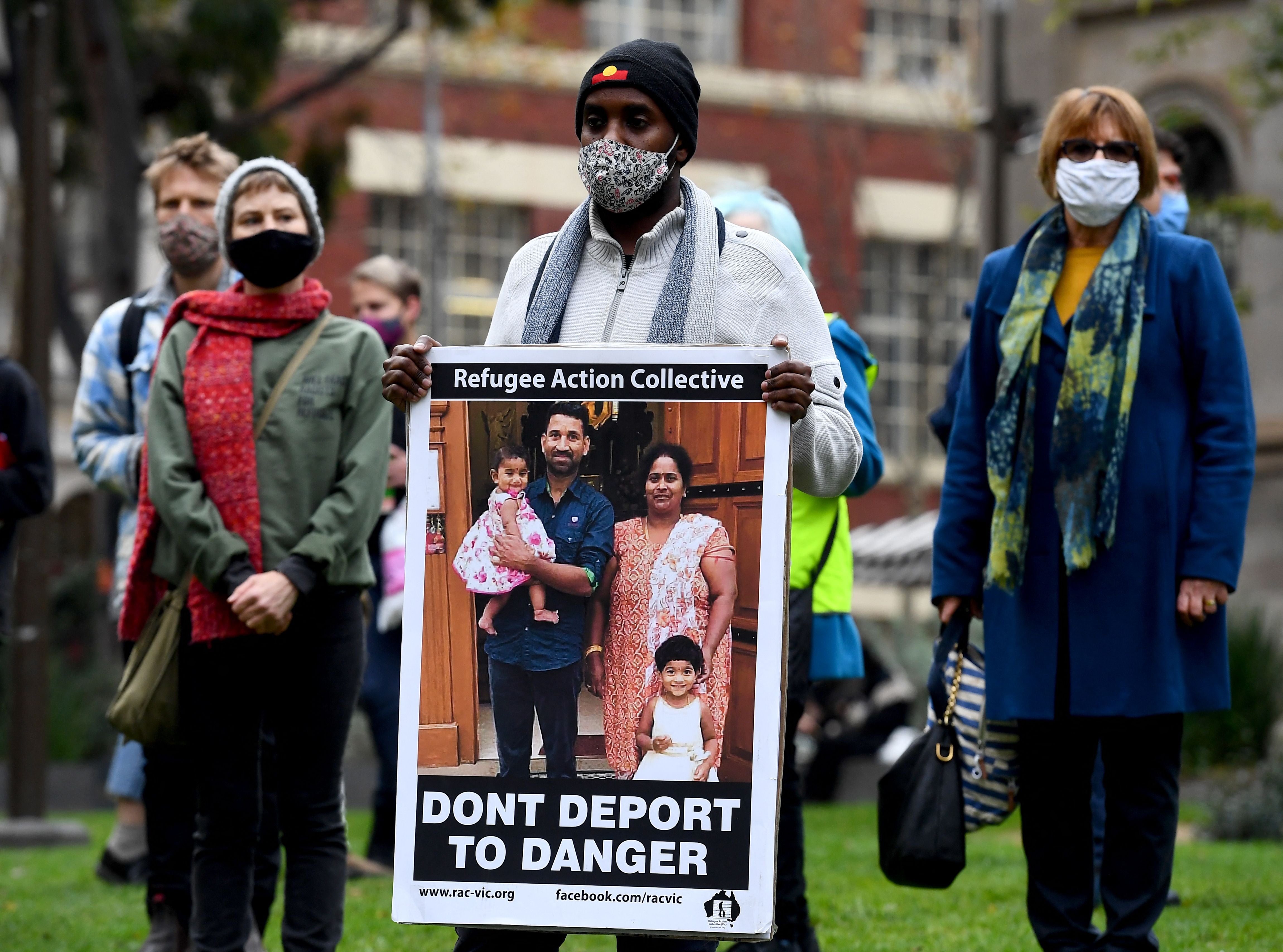 People hold up placards at a rally to support the Sir Lankan origin Tamil family living in detention