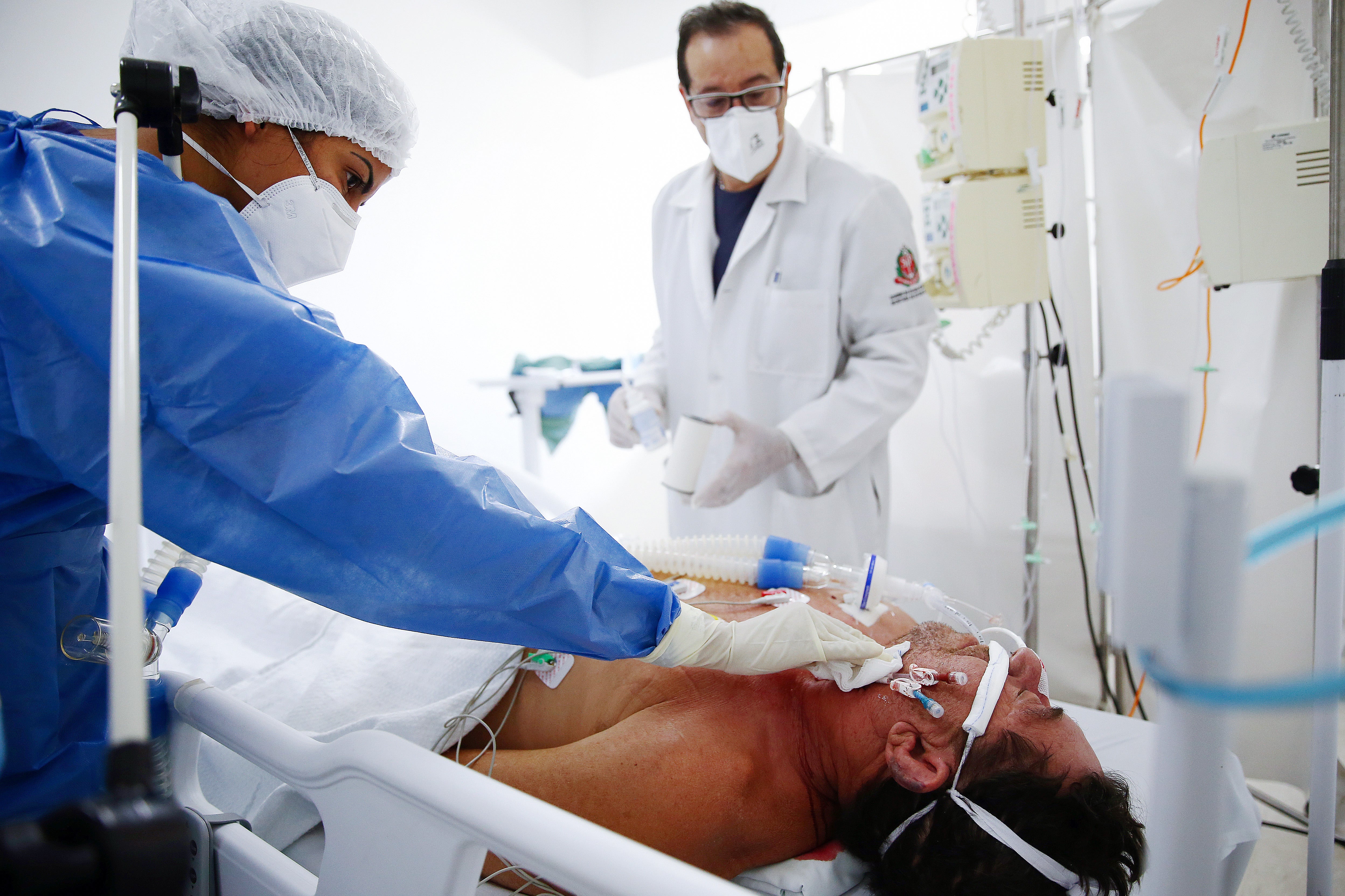 Nurse technician Larissa Bezerra (L) and nursing supervisor Mauricio Fernandes care for a Covid patient in the Intensive Care Unit (ICU) of a former men’s hospital, which has been converted into a field hospital for Covid patients in Sao Paulo, Brazil