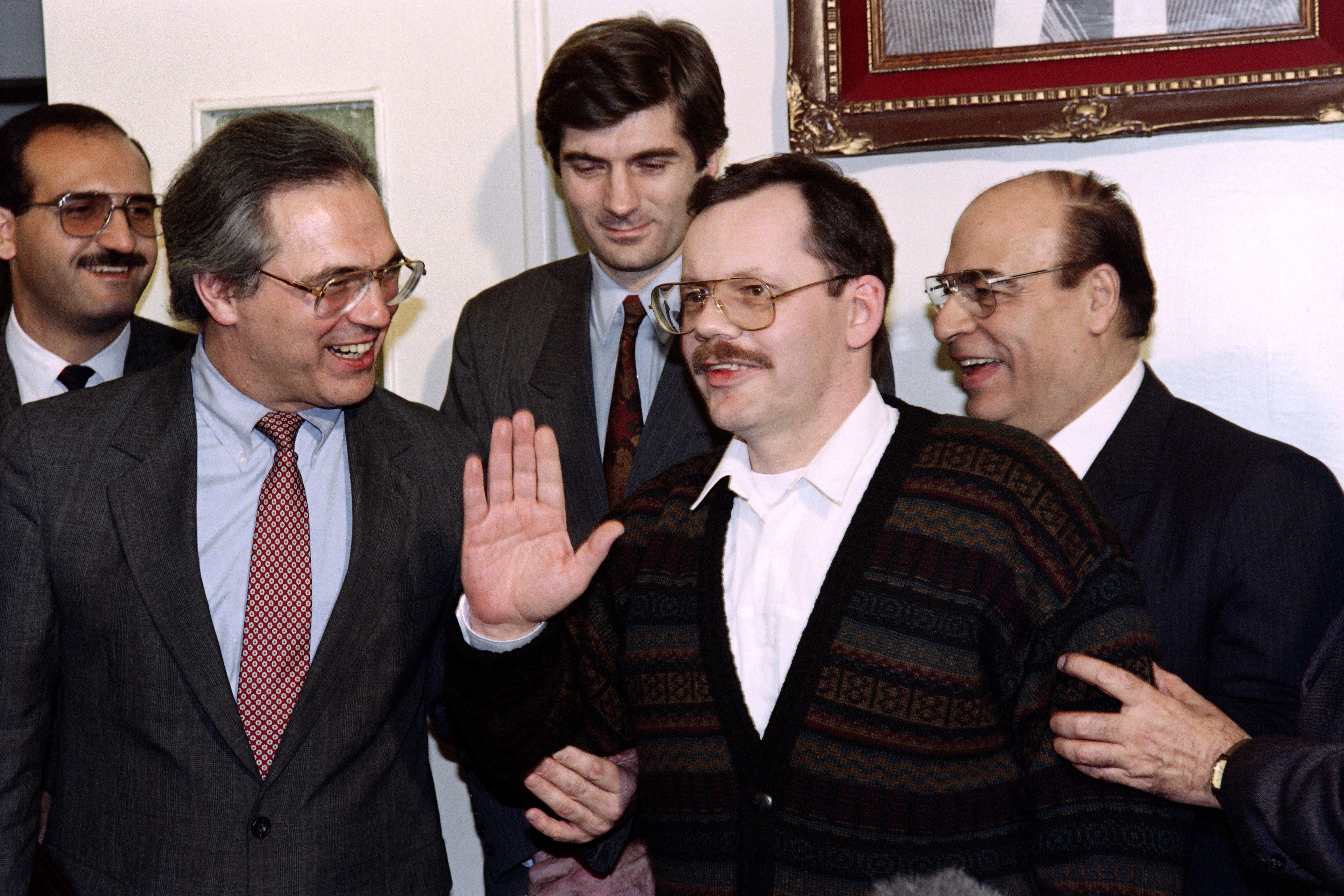 Terry Anderson waves to well-wishers during a press conference, on 4 December 1991 in Damascus as US ambassador Christopher Ros (left), UN hostage negotiator Giandomenico Picco (second left) and Syrian minister of state Youssef Shakour look on
