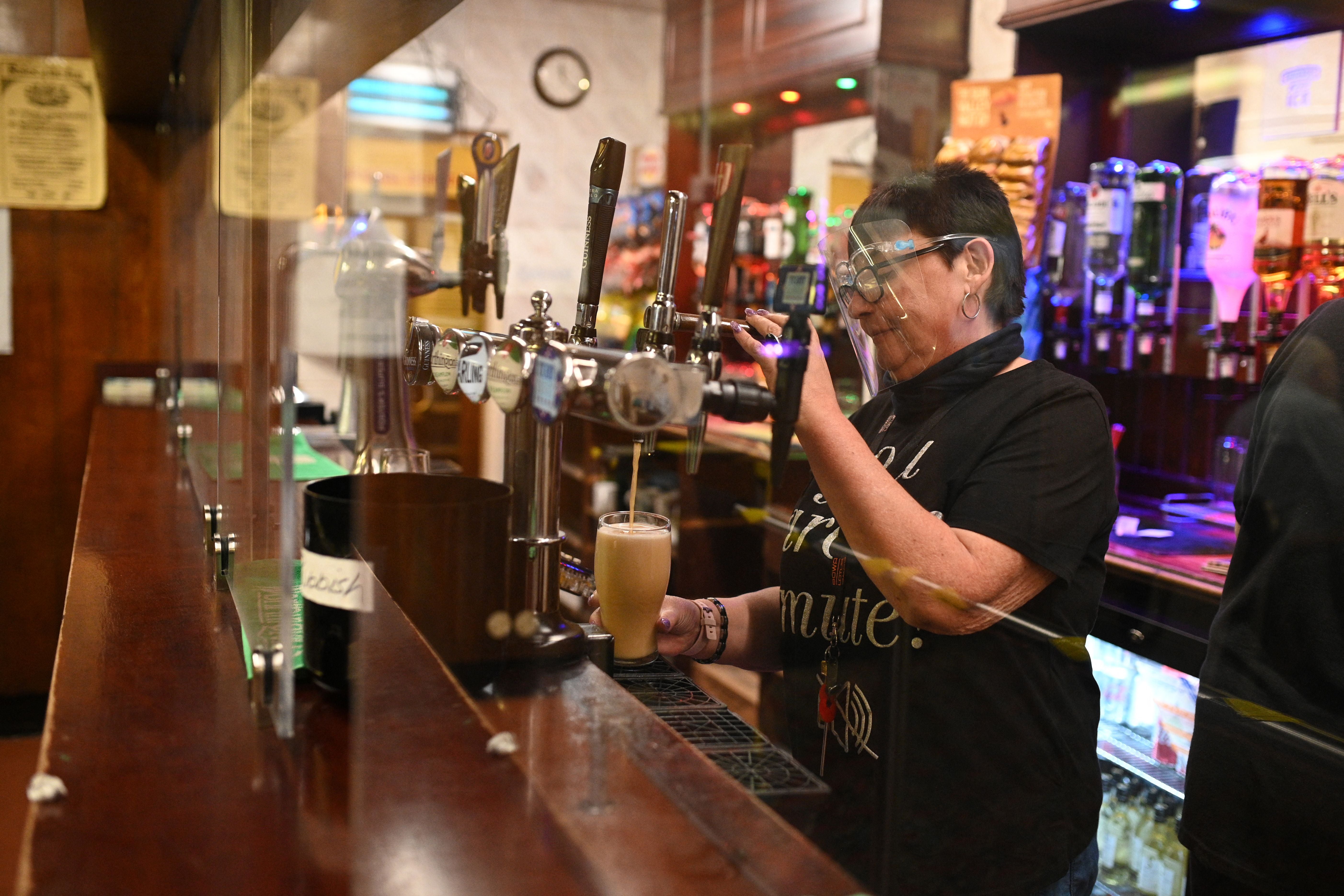 A member of staff pours a drink behind a perspex screen at the Harehills Labour Club Leeds on 17 May, 2021.