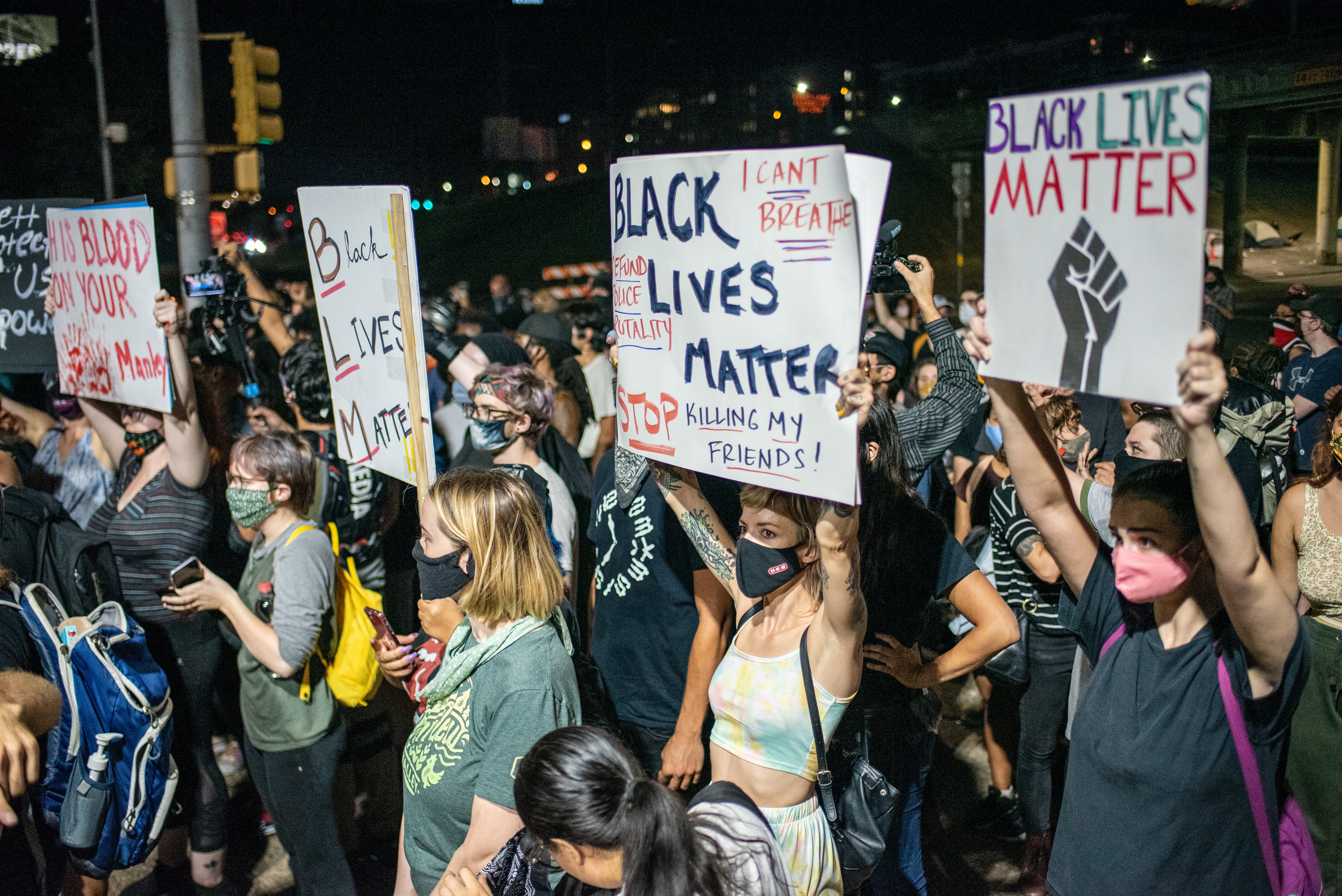 People hold up signs outside Austin Police Department after a vigil for Garrett Foster in July of 2020