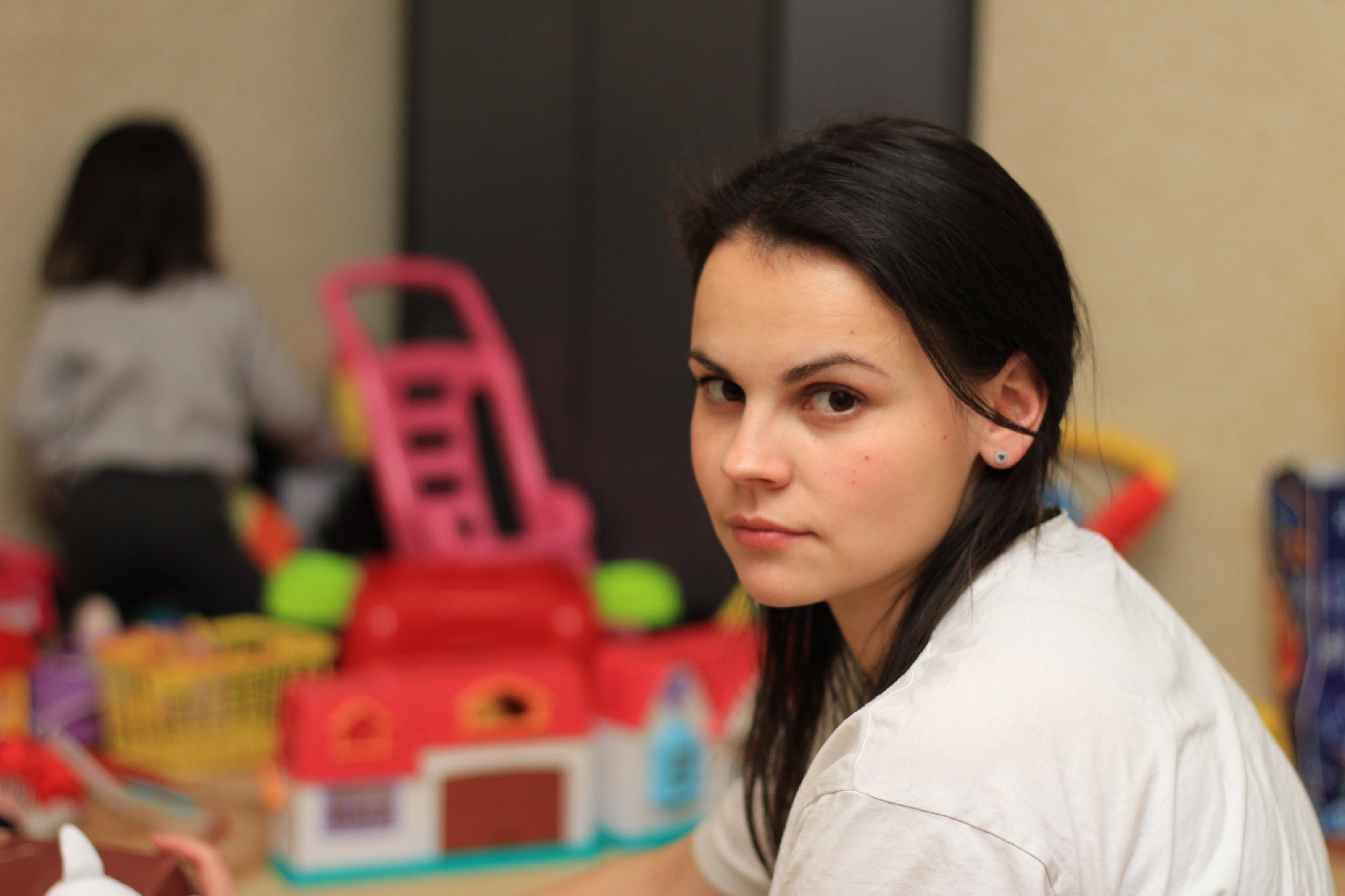 Young mum looking towards the camera as child plays in background