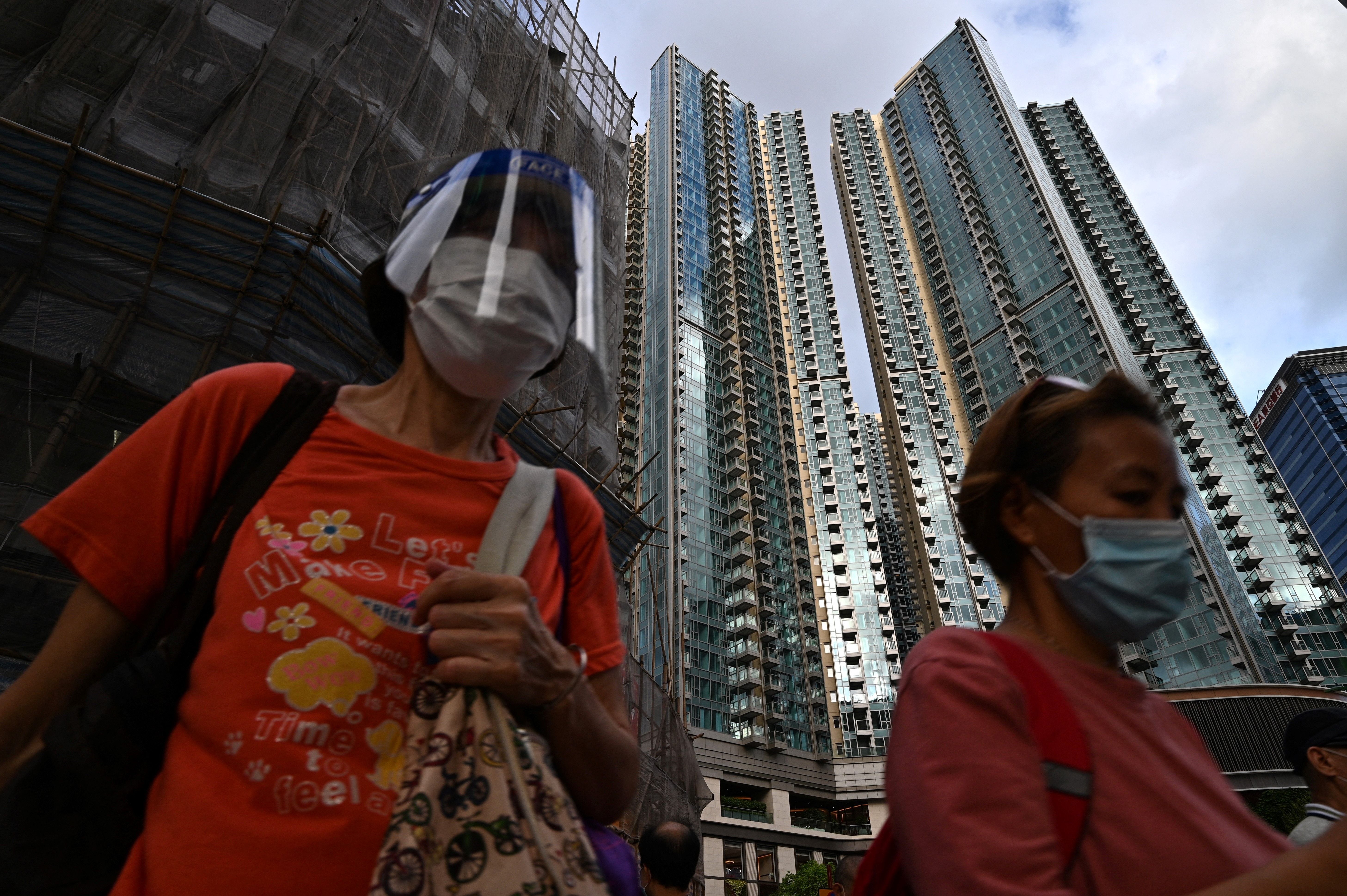 Pedestrians walk past the Grand Central residential building complex in Hong Kong on 28 May 2021, where a $1.4m one-bedroom apartment has been offered for a lucky draw's grand prize for which all Hong Kong residents aged 18 and above who have received both doses of the Covid-19 vaccines will be eligible to register