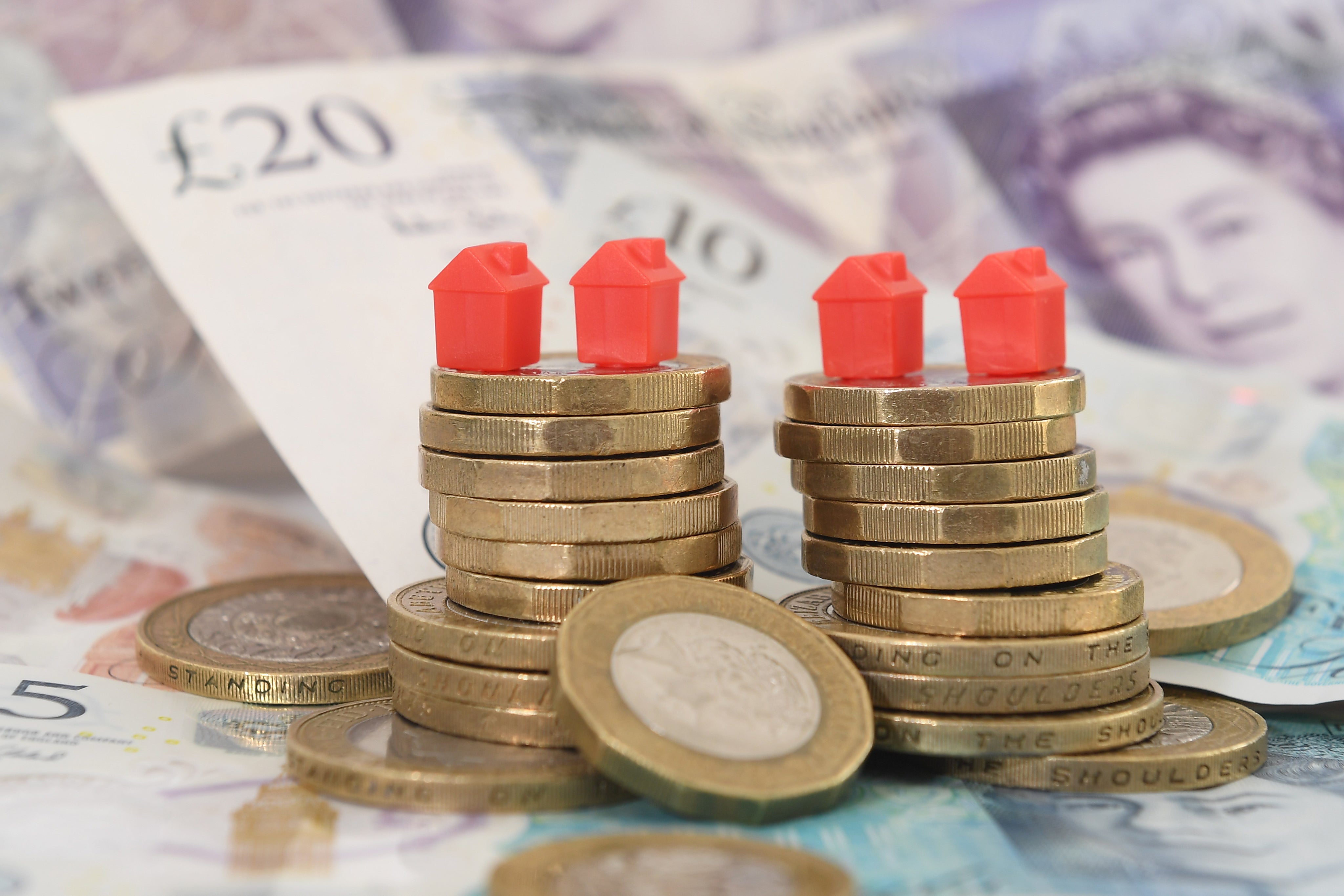 Model houses on piles of coins and banknotes