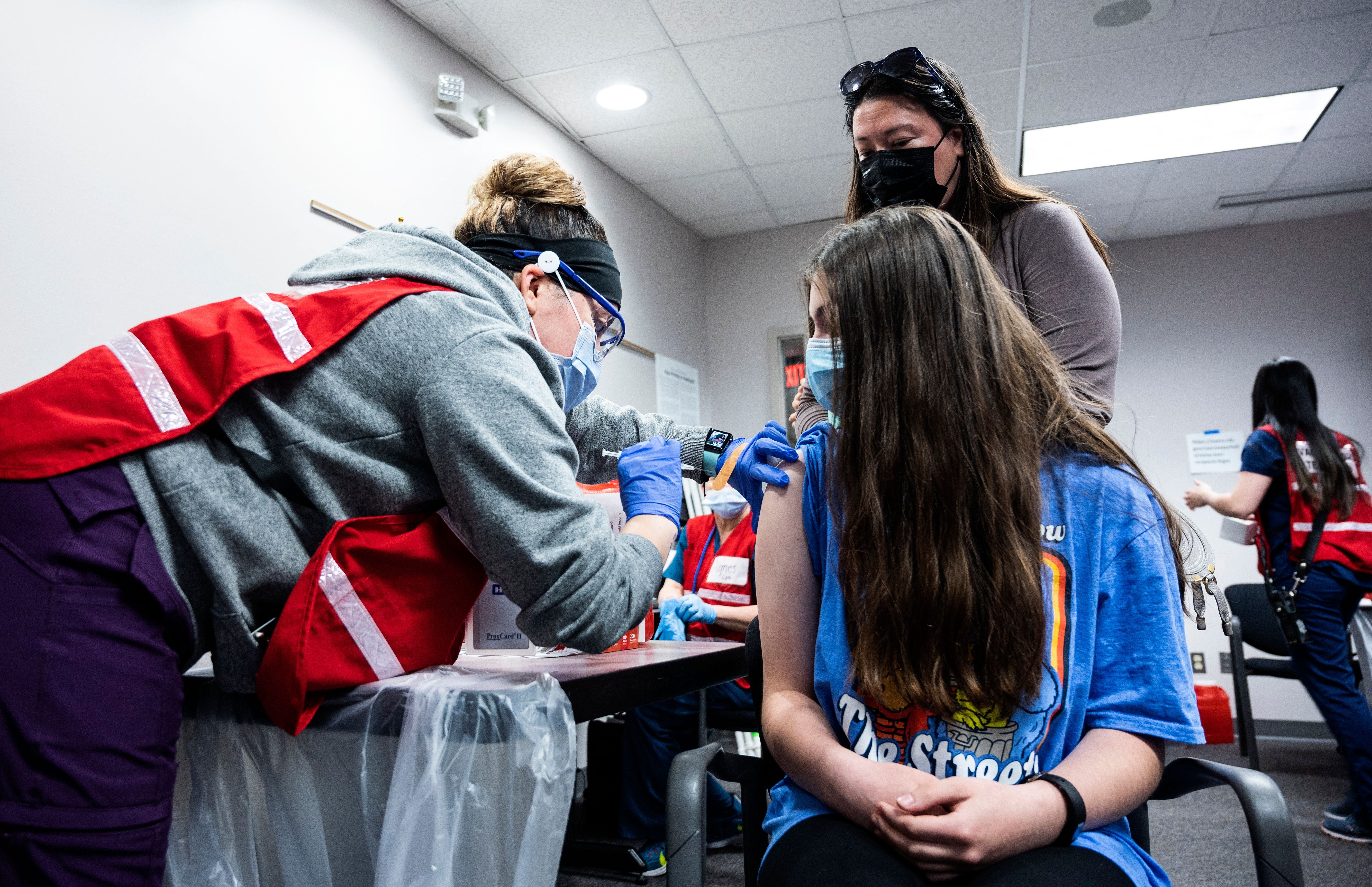 A mother looks on as her daughter gets a Covid-19 vaccination in Virginia on 13 May, 2021. A new poll has found that a quarter of adults in the United States do not intend to get their children vaccinated against Covid-19