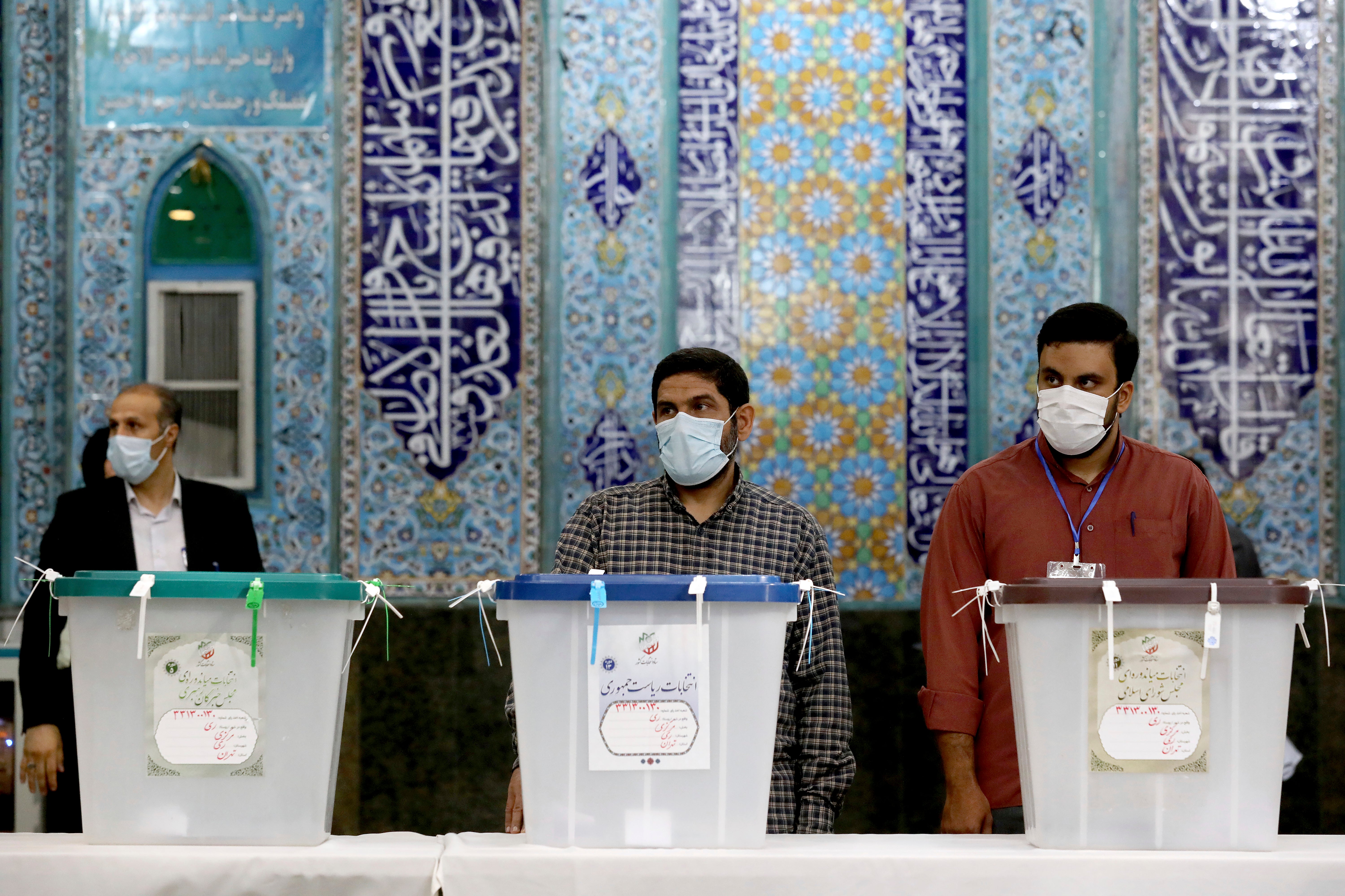 Iranian election officials wait for voters during the presidential election at a polling station in Tehran