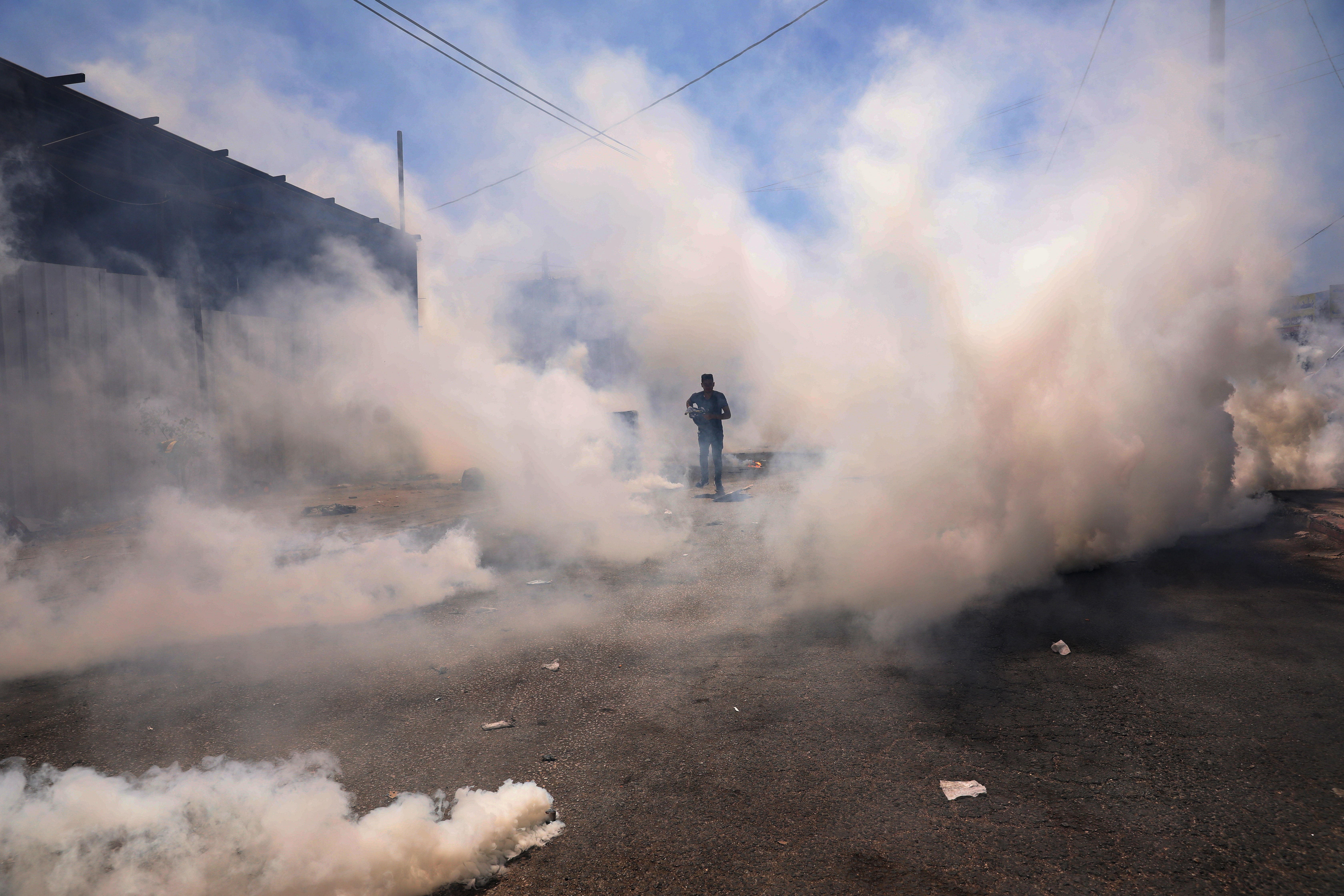 A Palestinian protester seeks cover from tear gas during clashes with Israeli troops after a protest against Israeli settlements at Beta village near the West Bank City of Nablus