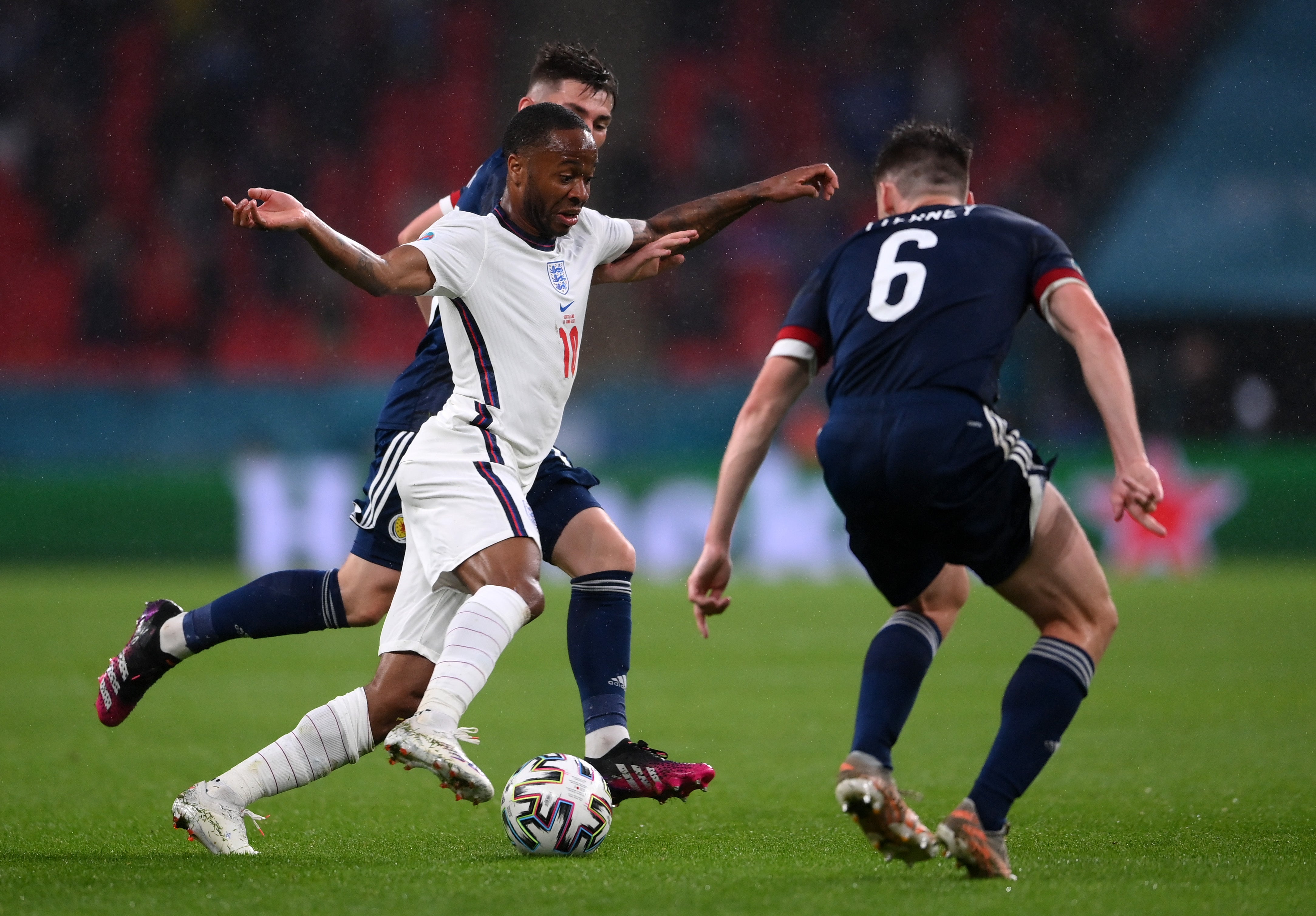 Raheem Sterling runs with the ball whilst under pressure from Kieran Tierney