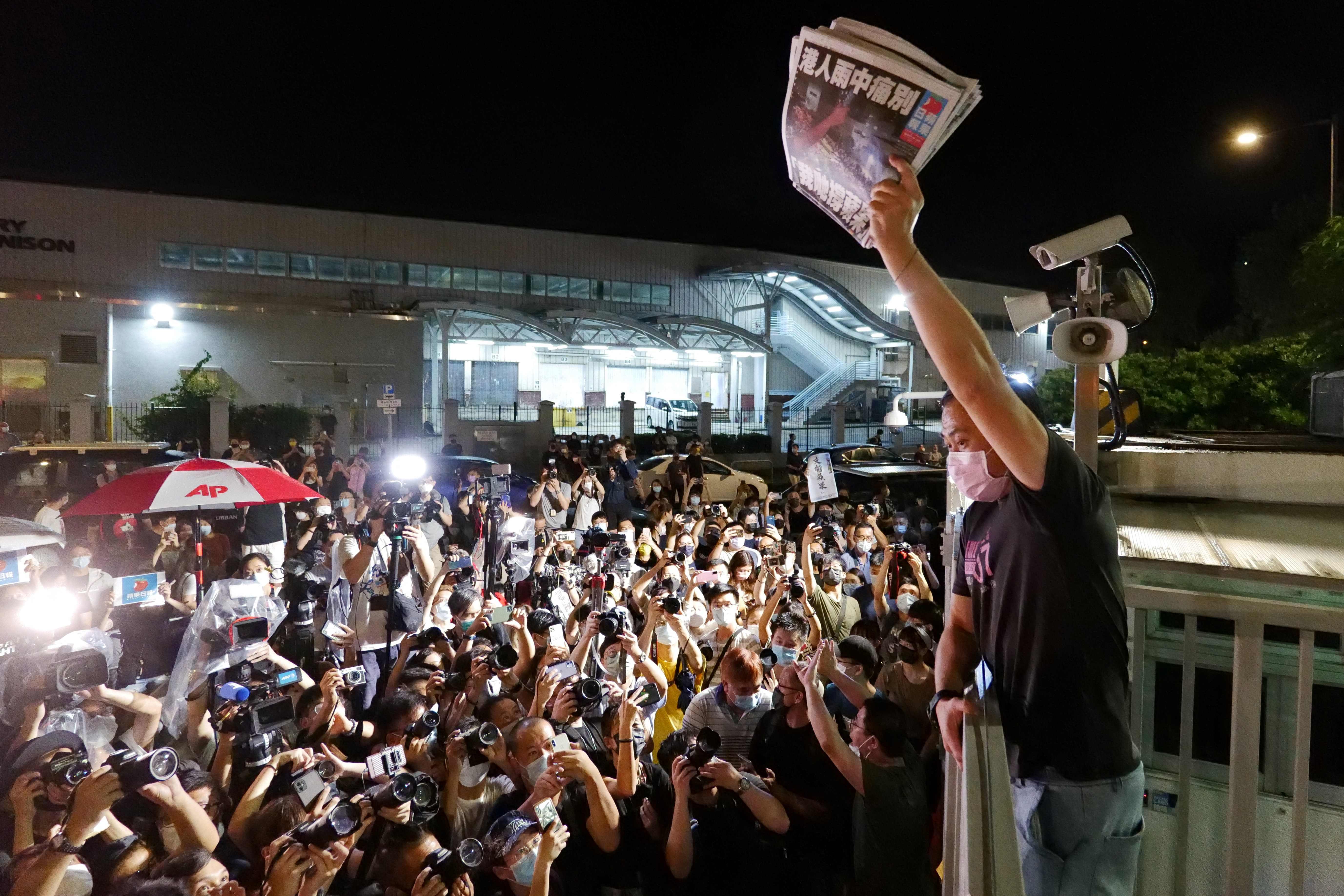 An Apple Daily journalist holds freshly-printed copies of the newspaper’s last edition to be distributed to supporters gathered outside their office in Hong Kong early on 24 June