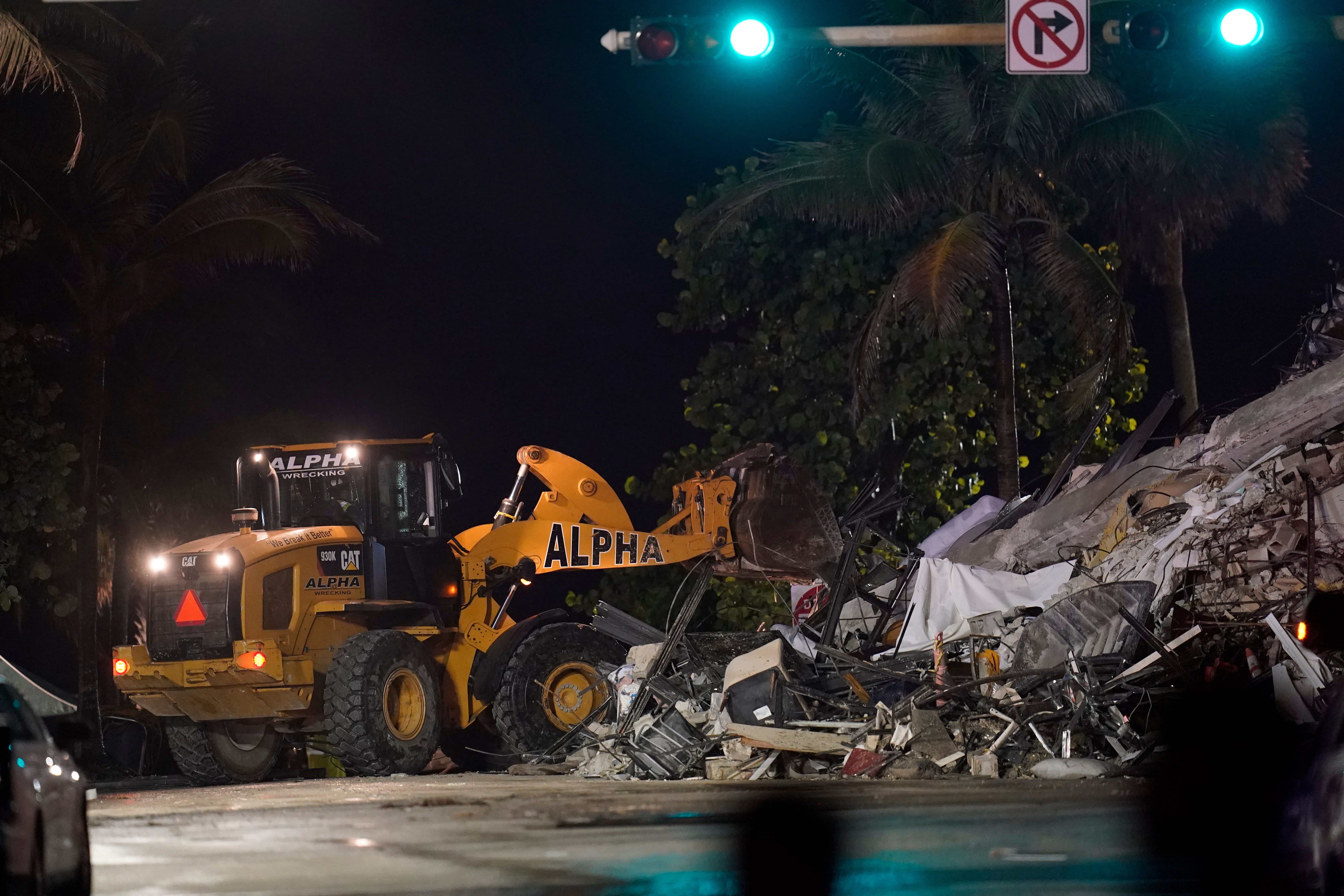 A front end loader shifts rubble mixed with furniture and household items