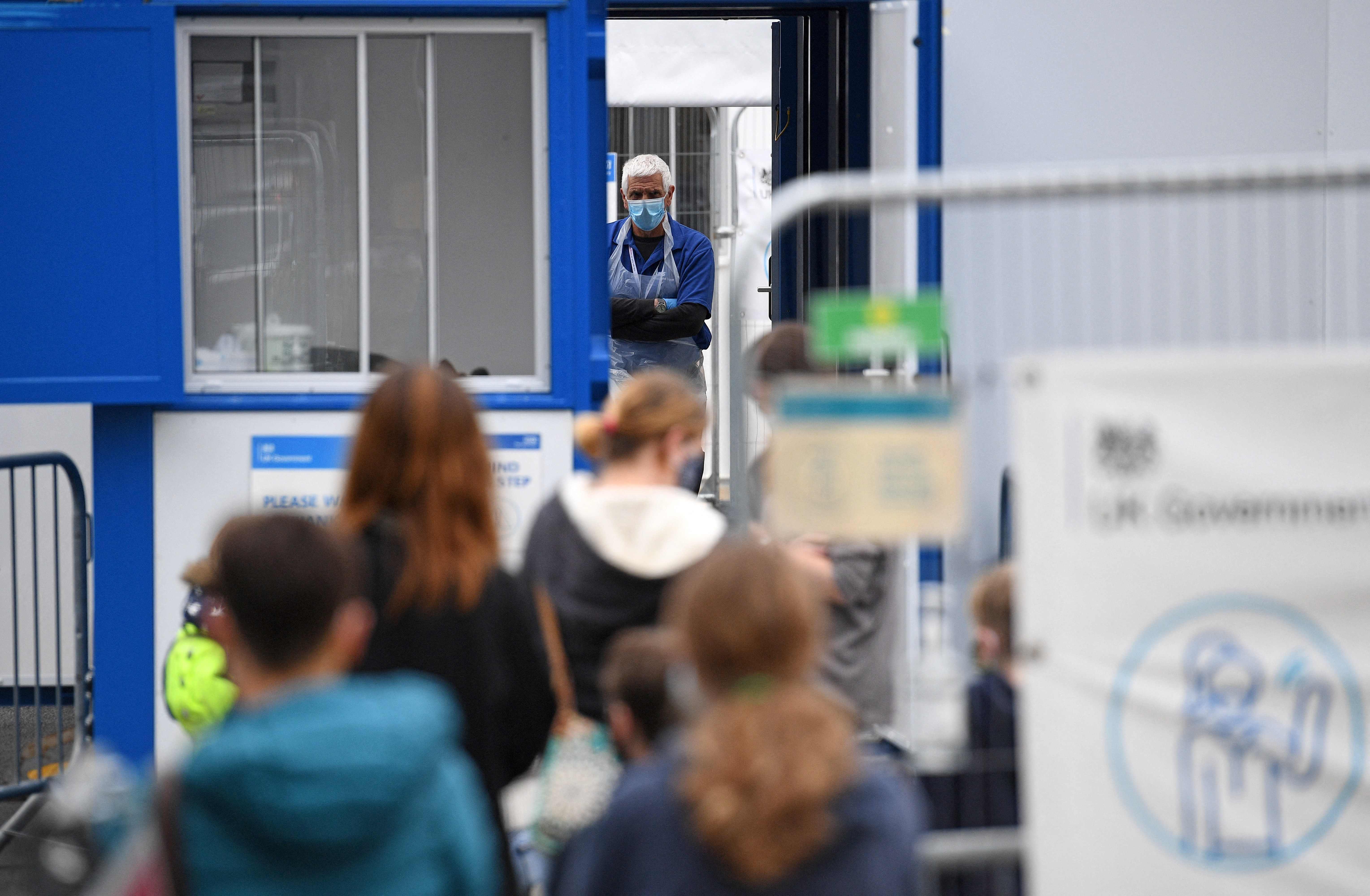 Members of the public queue to enter a temporary Covid-19 testing centre set up a car park in Kendal in Cumbria