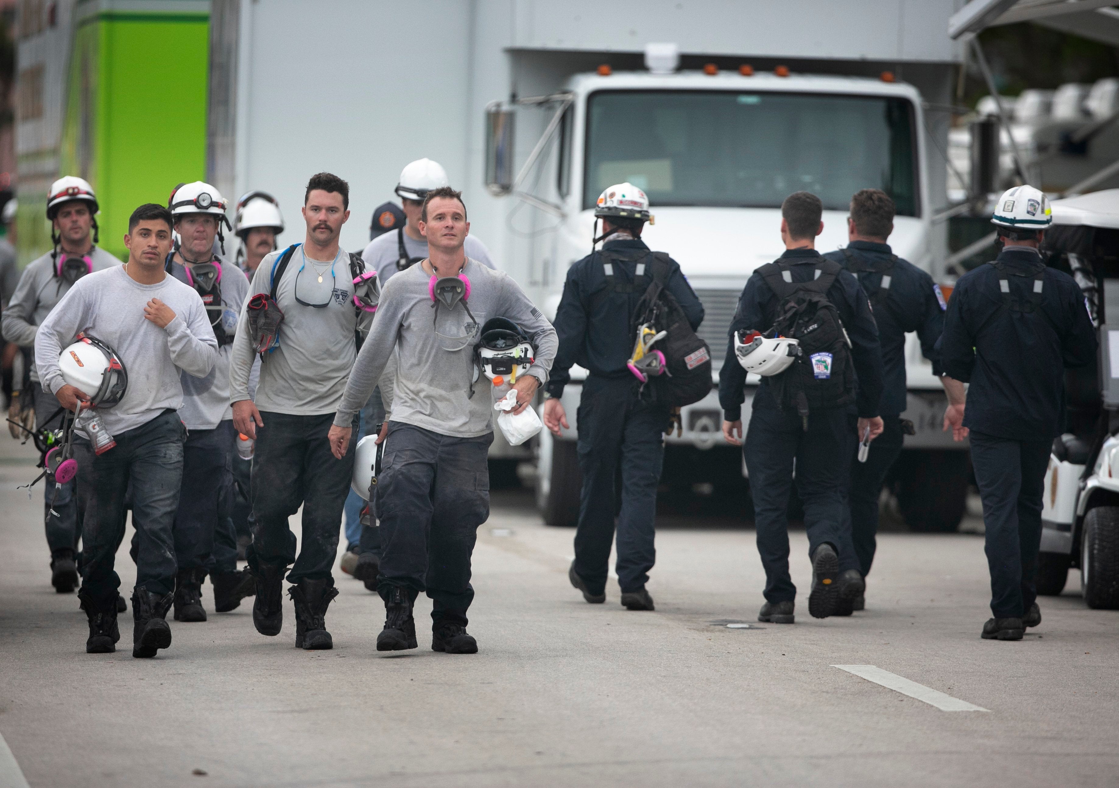 Search and rescue crews from the Jacksonville Fire Dept and members of Florida Task Force 5 walk out of the work area as another crew heads in