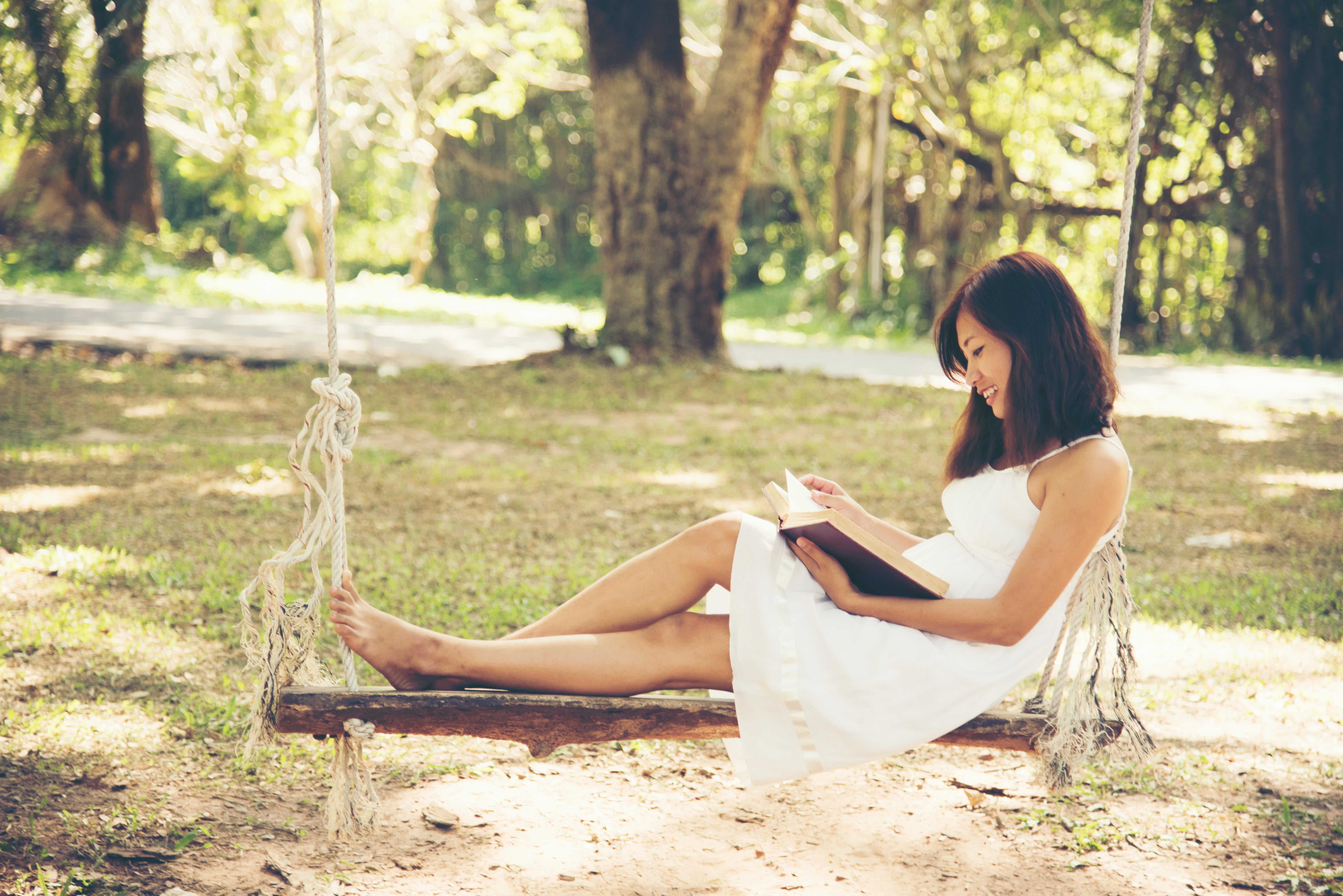 Woman sitting on a swing reading a book